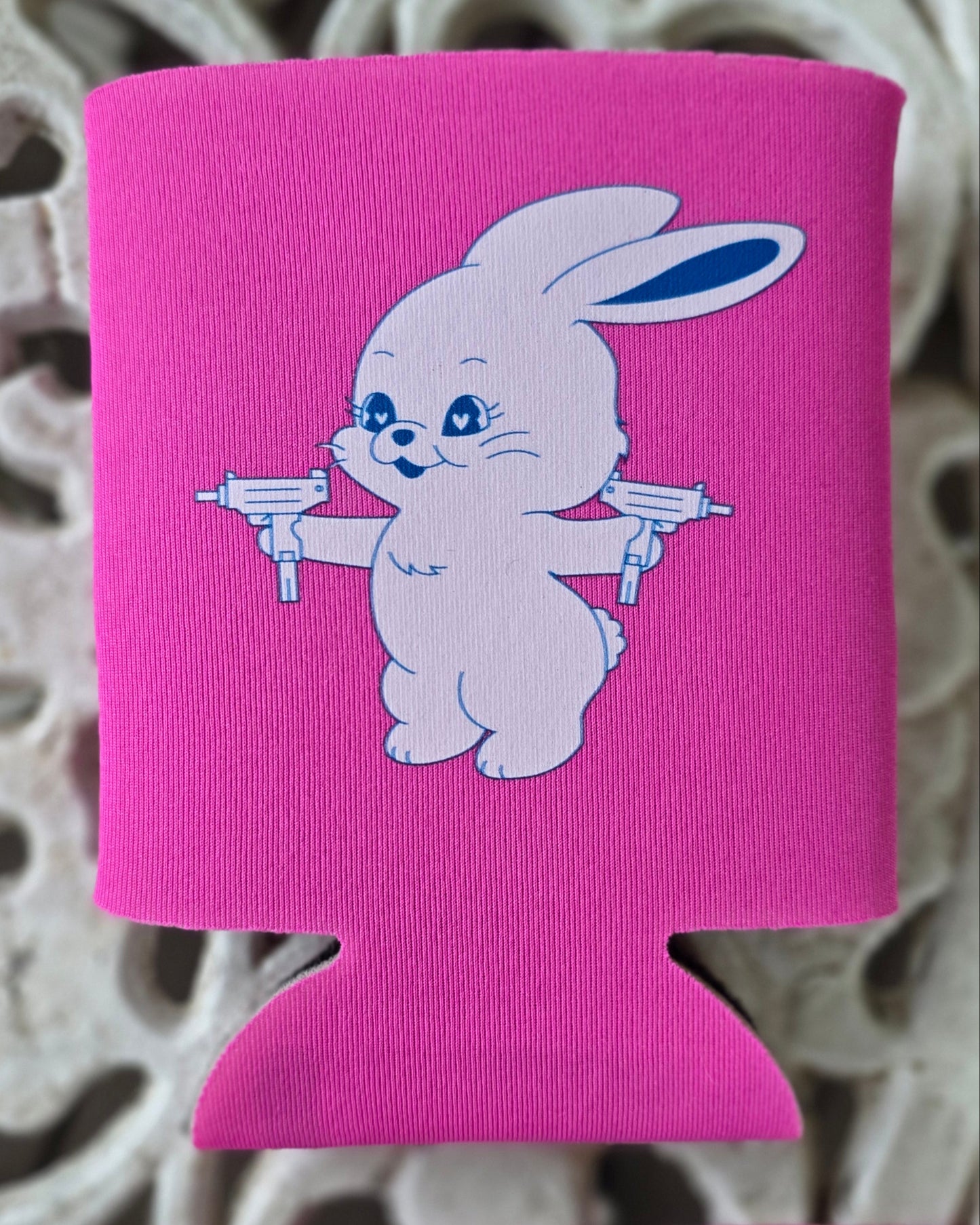 Pink can cooler with a white rabbit design on a decorative surface