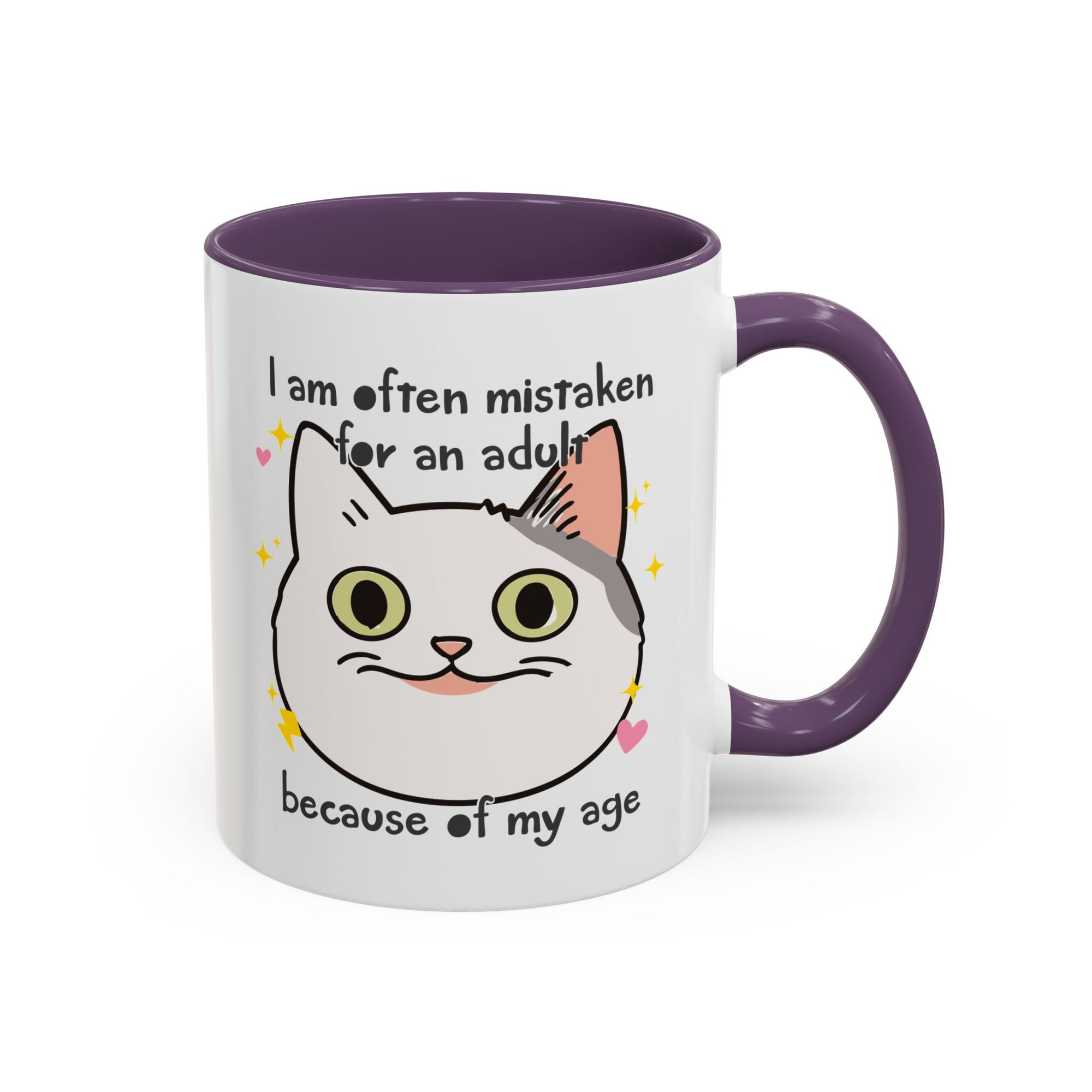 White ceramic mug with purple handle and interior featuring a cute wide-eyed cat face, hearts, sparkles, and the phrase “I am often mistaken for an adult because of my age.”
