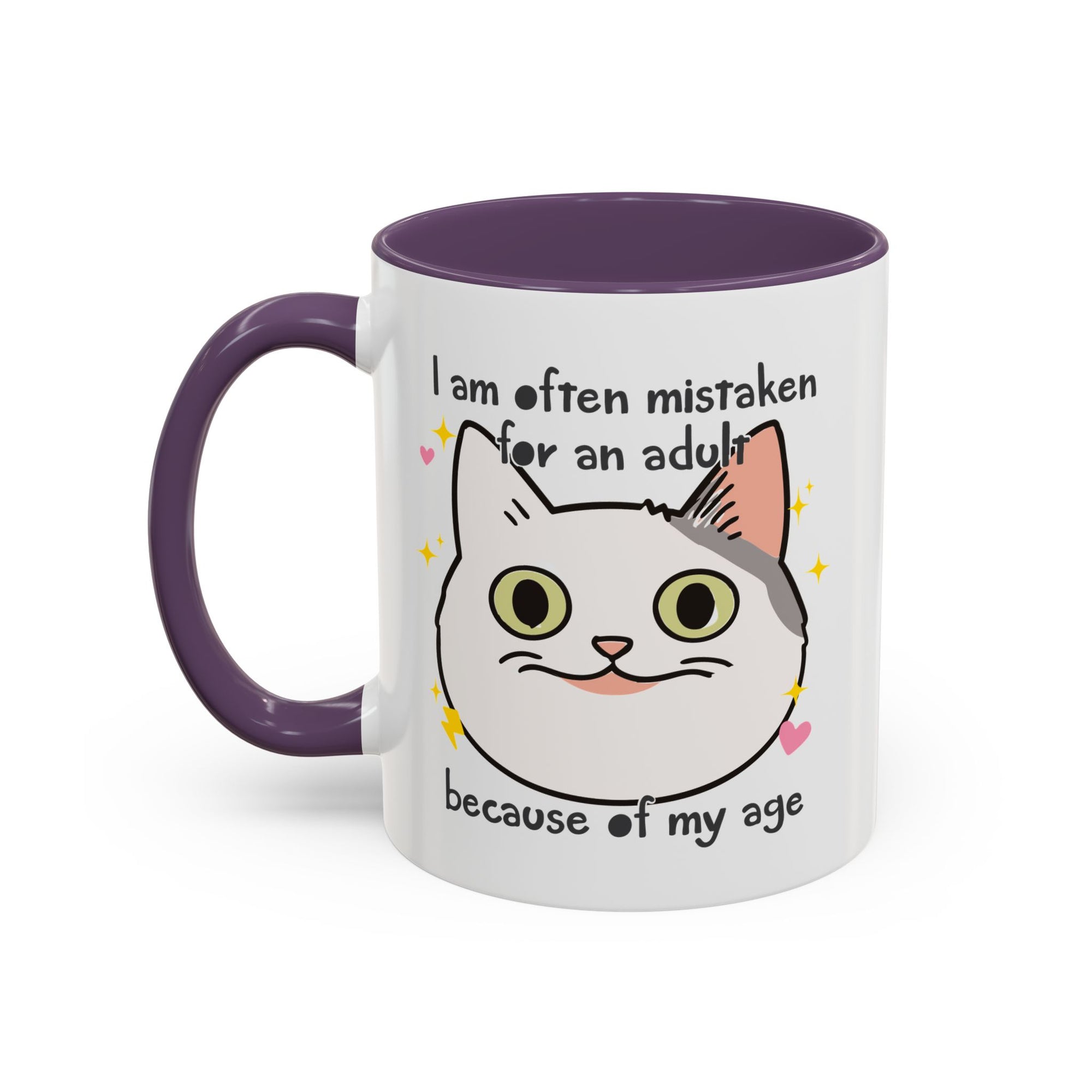 White ceramic mug with purple handle and interior featuring a cute wide-eyed cat face, hearts, sparkles, and the phrase “I am often mistaken for an adult because of my age.”
