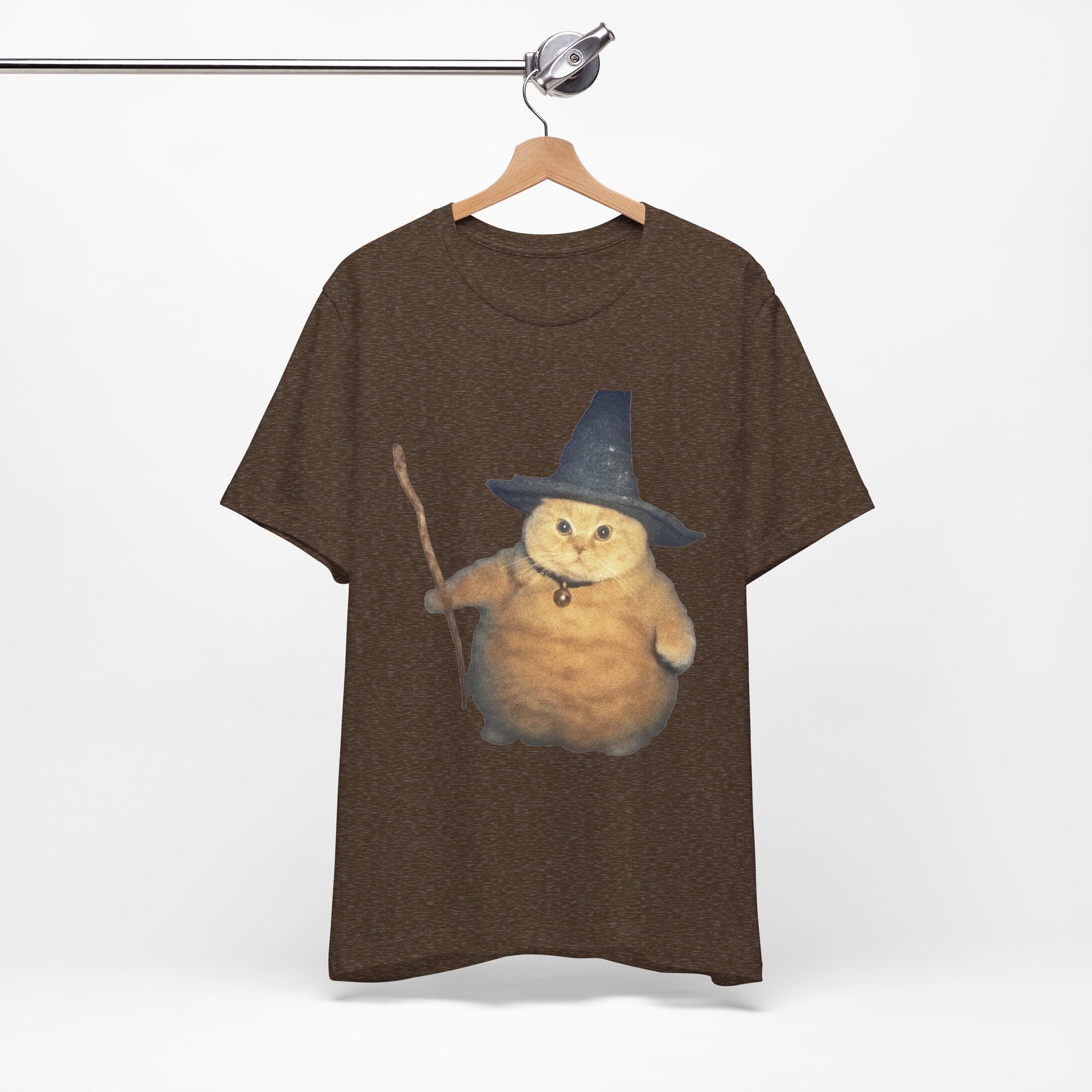 Brown t-shirt with a cat wearing a wizard hat and holding a staff on a hanger against a white background.
