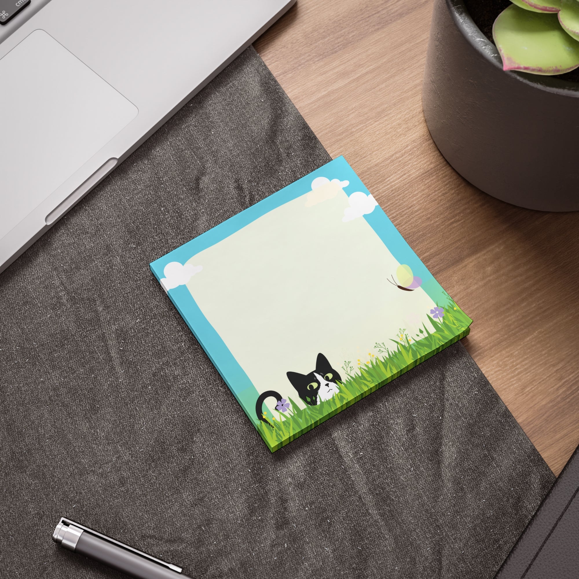 Stack of sticky notes with a black and white cat peeking from tall grass, flowers, clouds, and a light blank writing area in the center.
