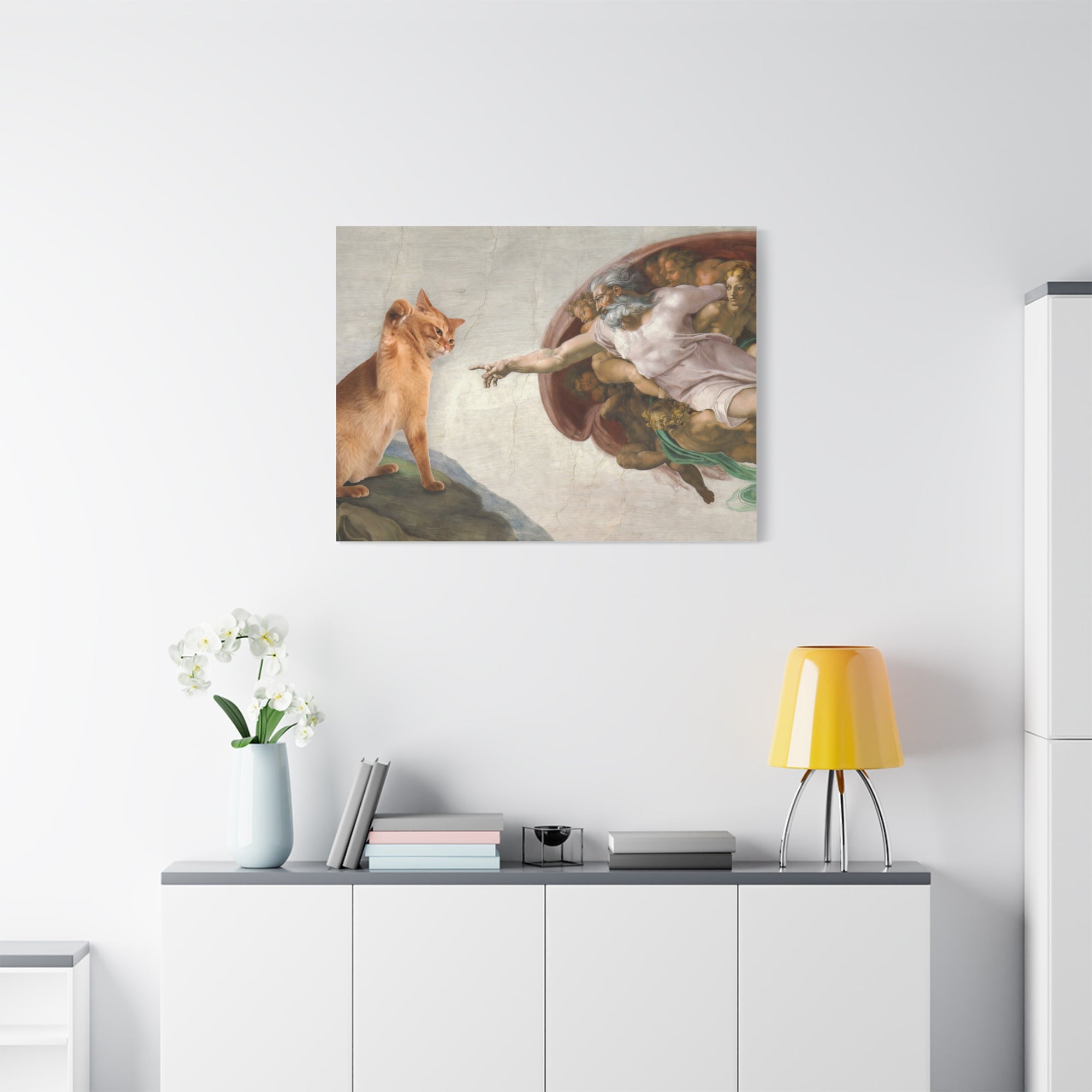 Framed artwork of a classical scene above a white cabinet with decorative items.