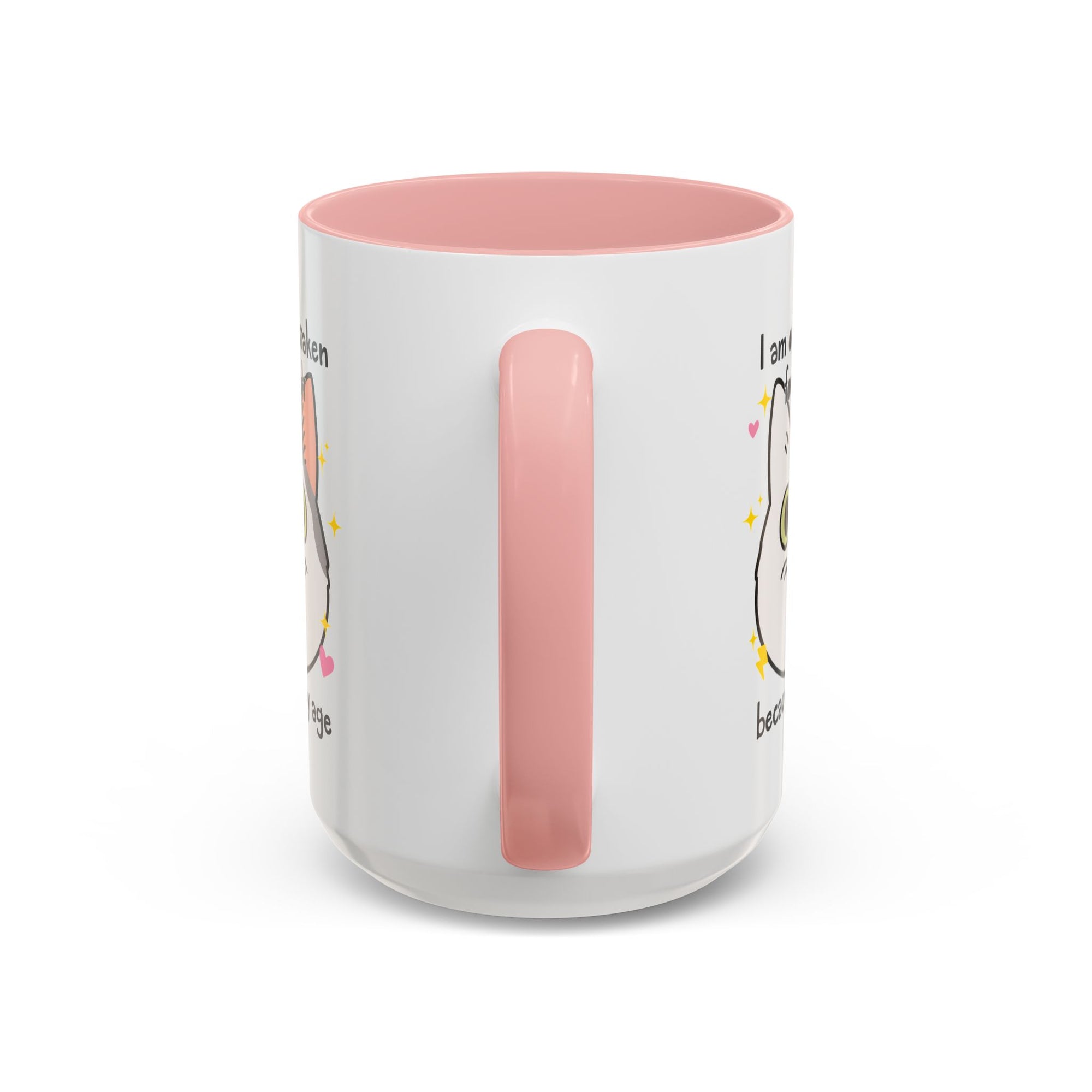 White ceramic mug with peach handle and interior featuring a cute wide-eyed cat face, hearts, sparkles, and the phrase “I am often mistaken for an adult because of my age.”
