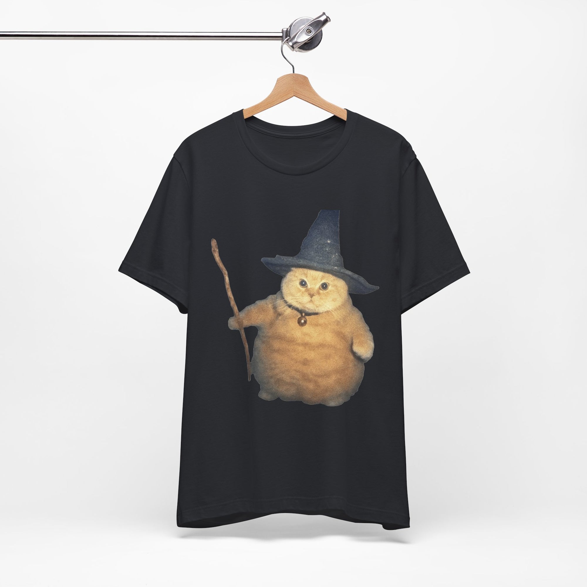 Black t-shirt with a cat wearing a witch hat and broomstick on a hanger against a white background