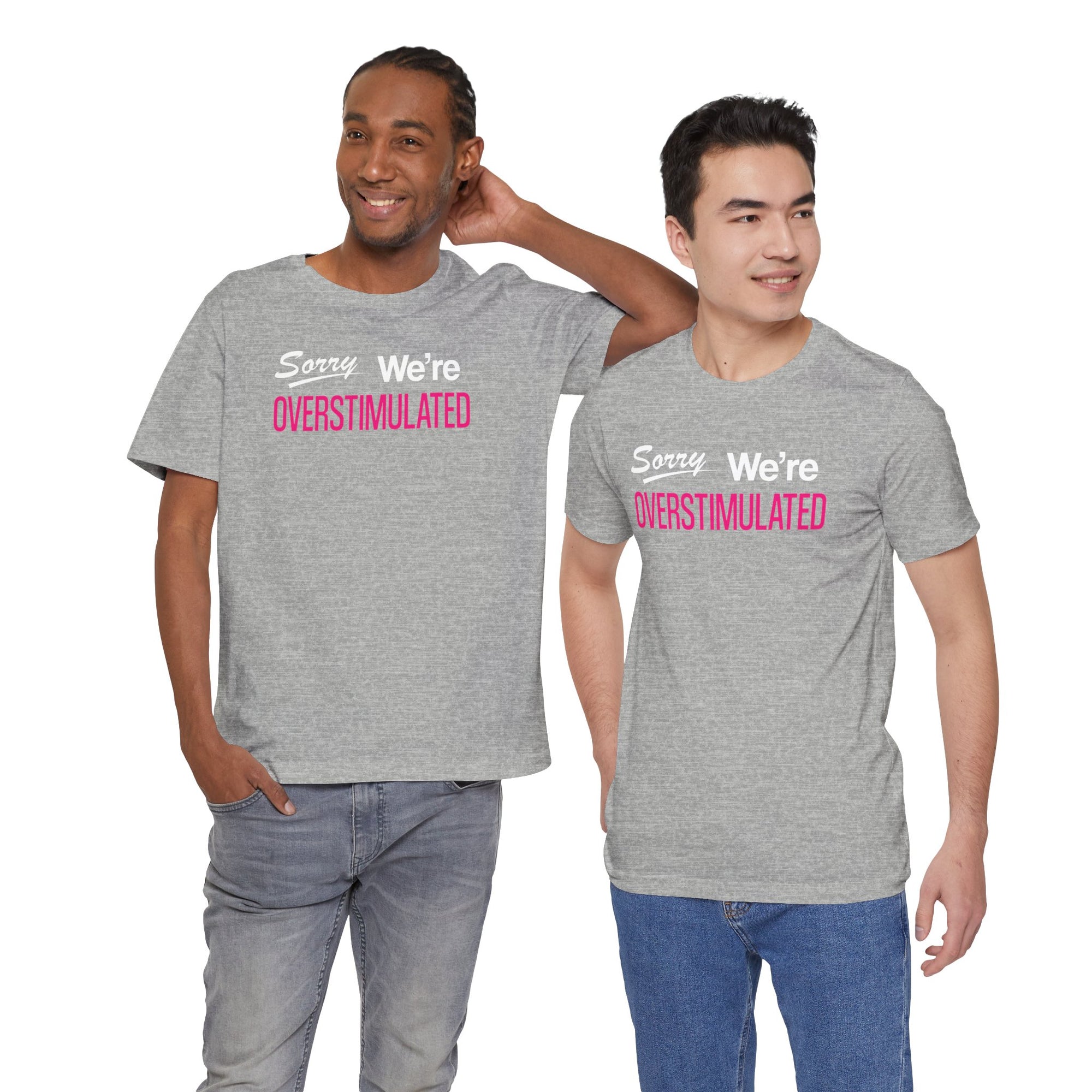 Two men wearing gray t-shirt featuring the phrase “Sorry We’re Overstimulated” in white and hot pink text.
