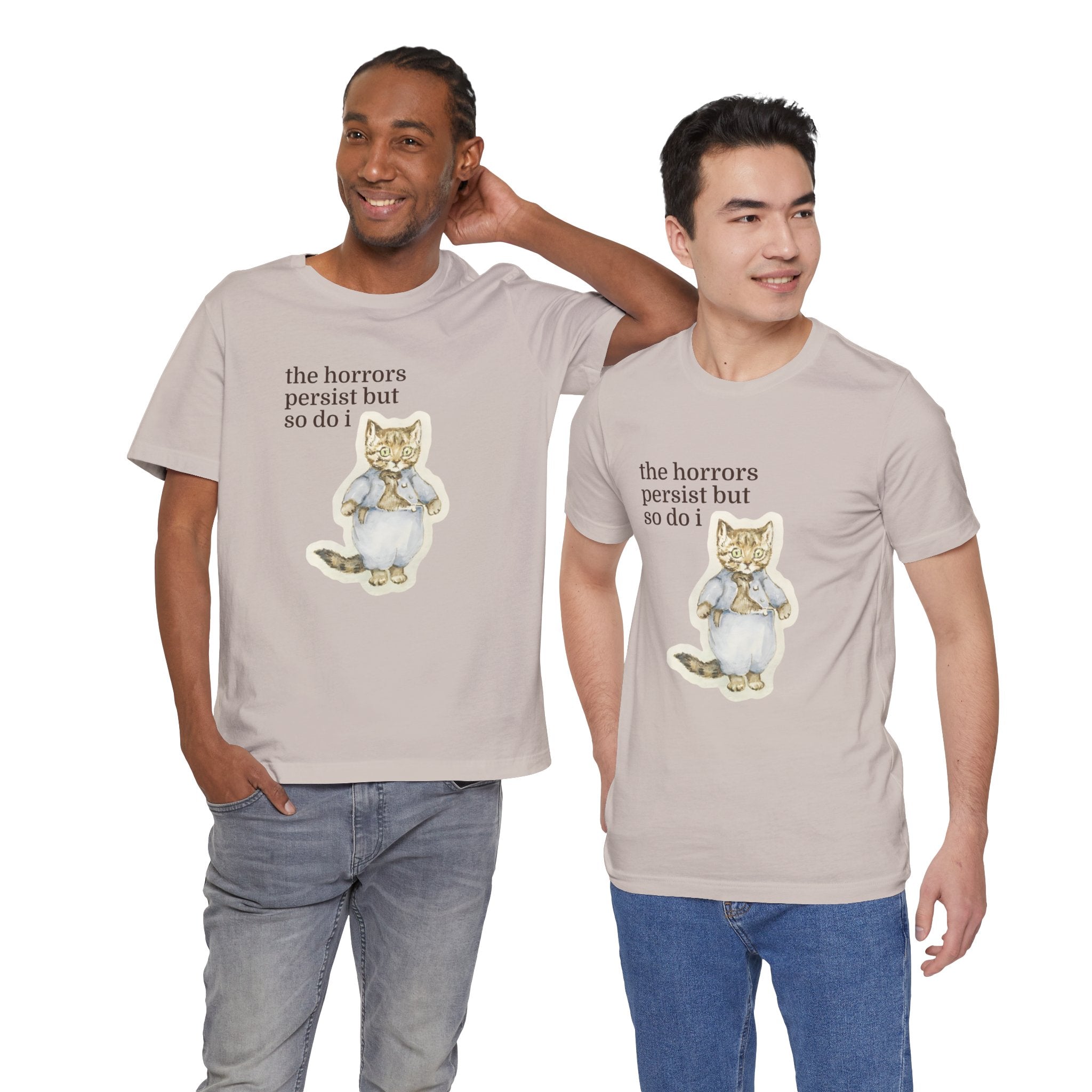 Two men wearing matching t-shirt featuring a vintage-style illustrated cat in blue clothing with the phrase “the horrors persist but so do i.”