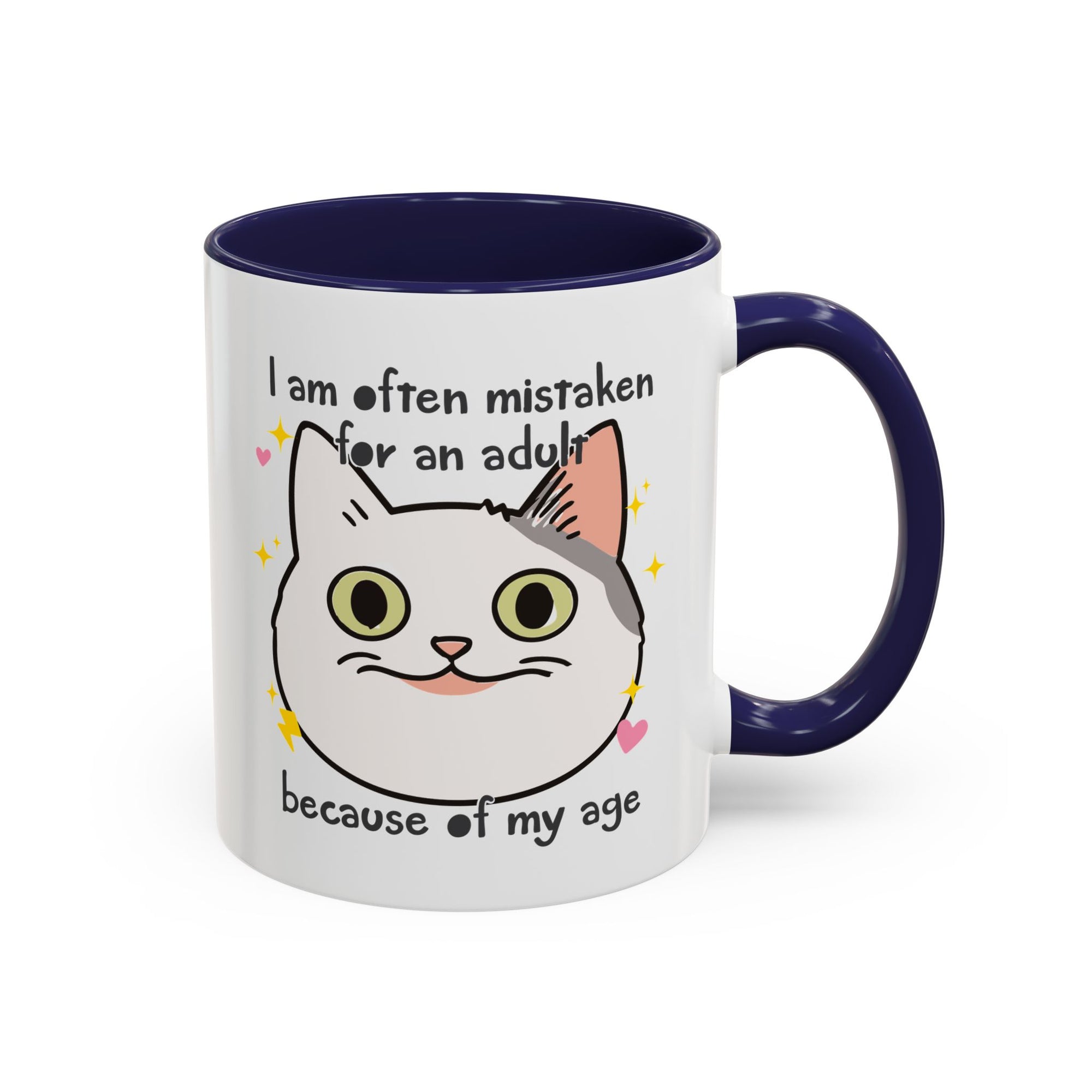 White ceramic mug with black handle and interior featuring a cute wide-eyed cat face, hearts, sparkles, and the phrase “I am often mistaken for an adult because of my age.”
