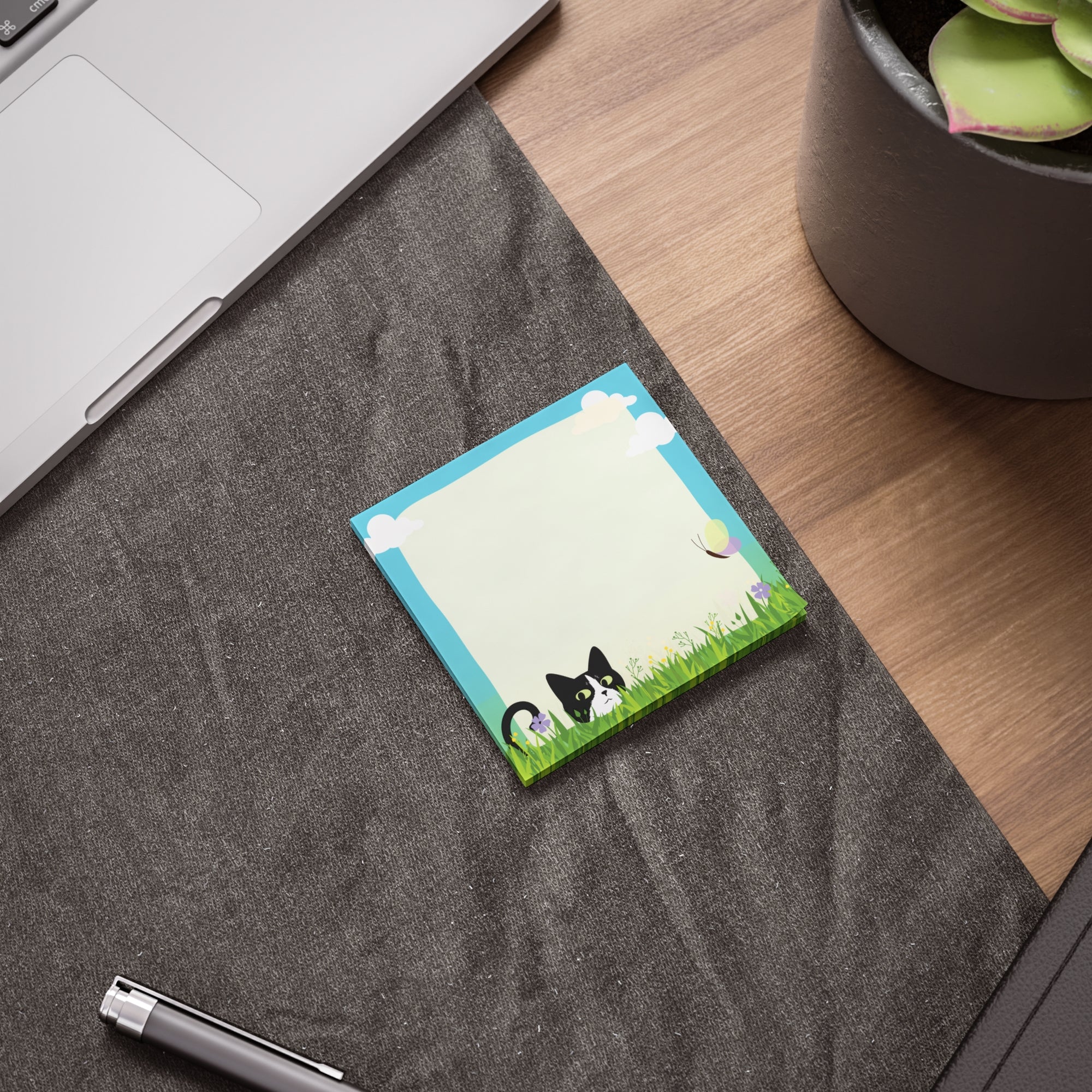 Stack of sticky notes with a black and white cat peeking from tall grass, flowers, clouds, and a light blank writing area in the center.
