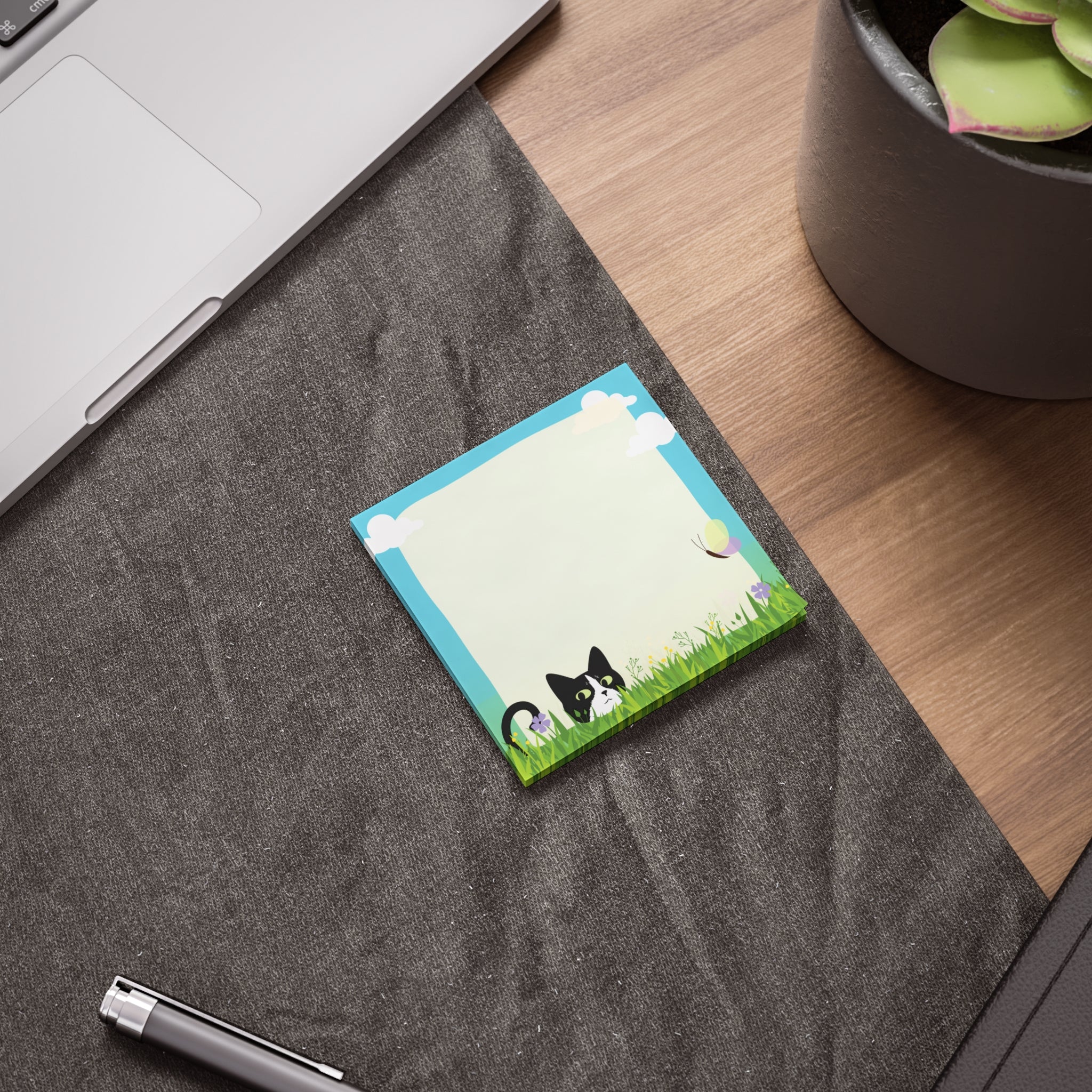 Stack of sticky notes with a black and white cat peeking from tall grass, flowers, clouds, and a light blank writing area in the center.

