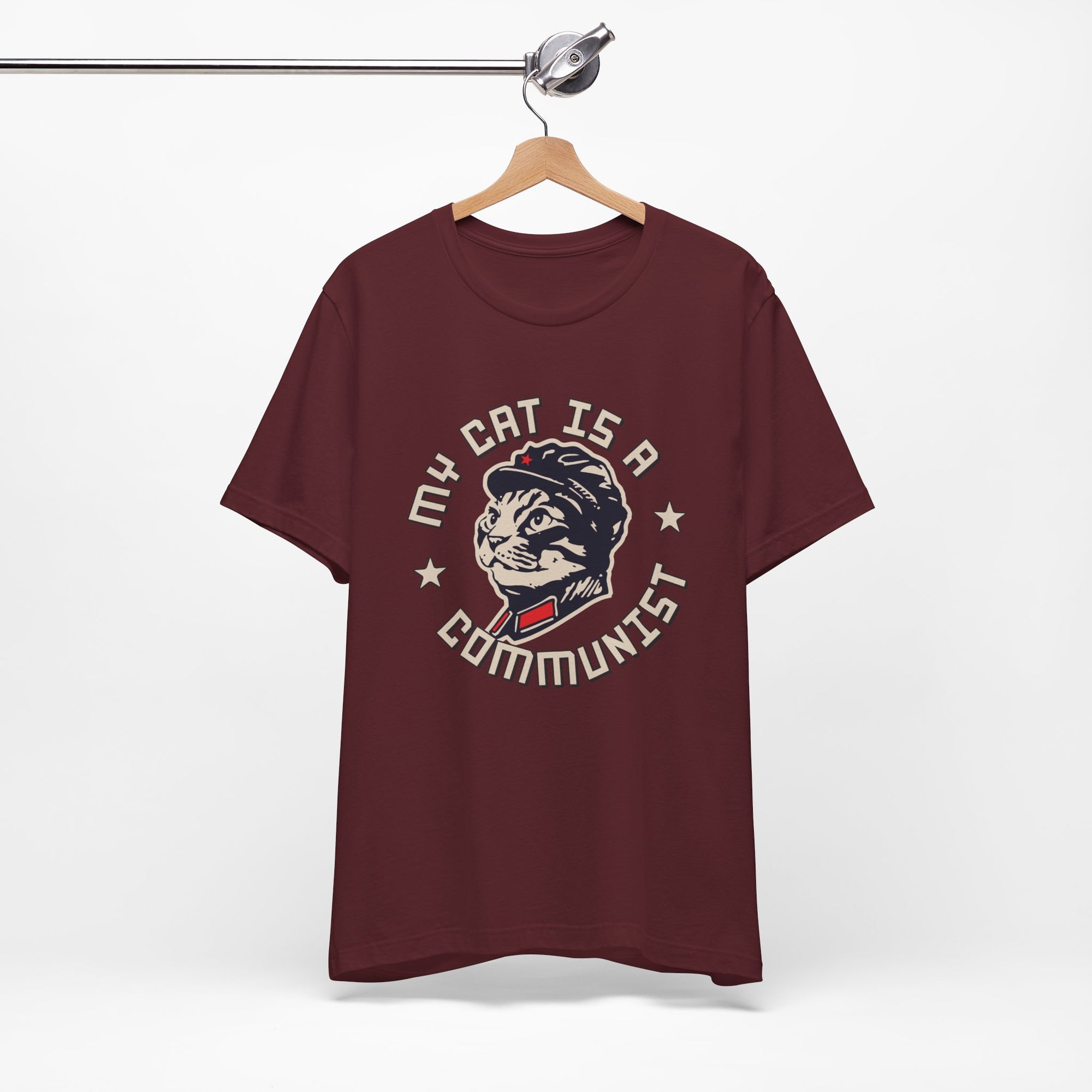 Maroon t-shirt with a graphic design of a cat and text on a hanger against a white background