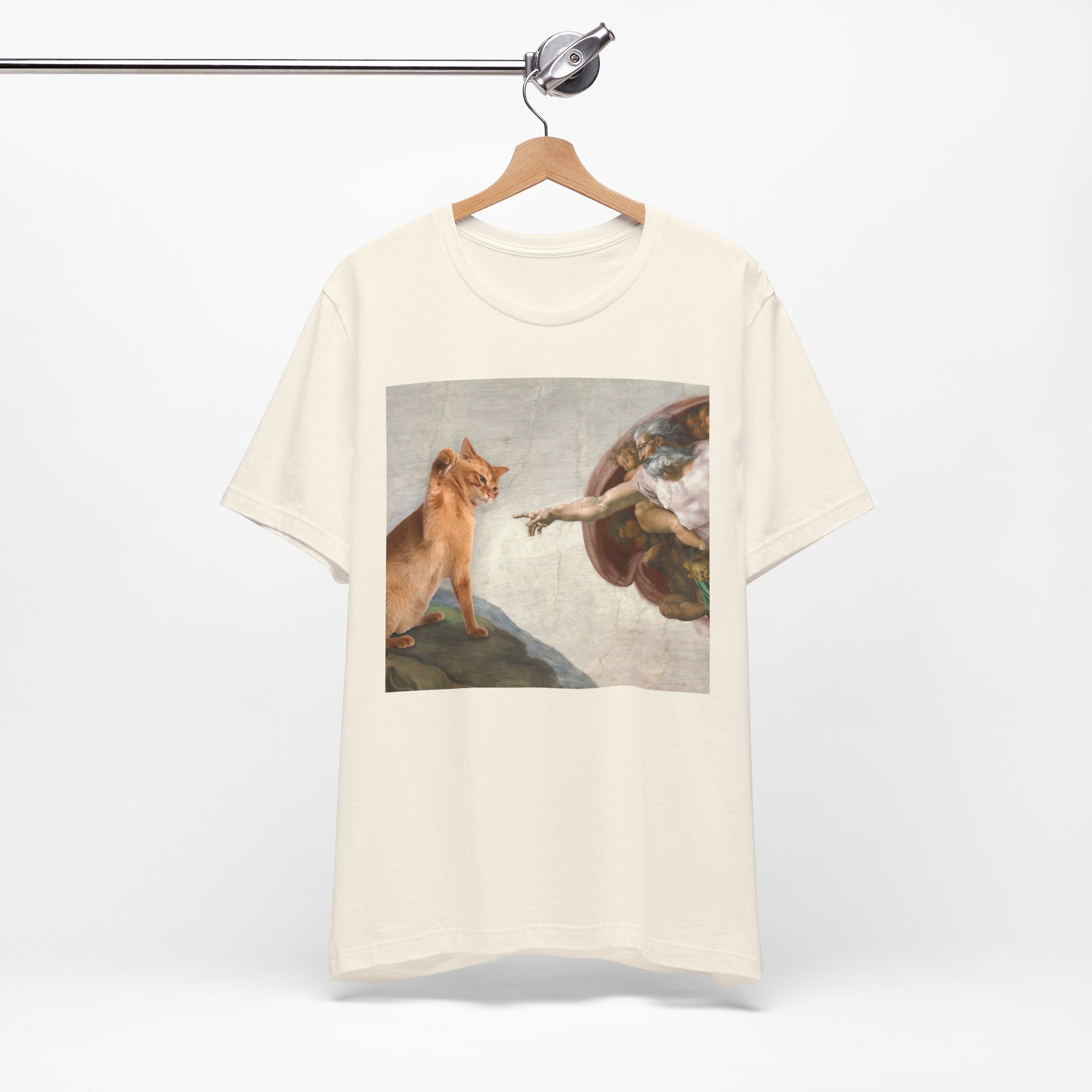 White t-shirt with a graphic of a cat and angel on a hanger against a white background