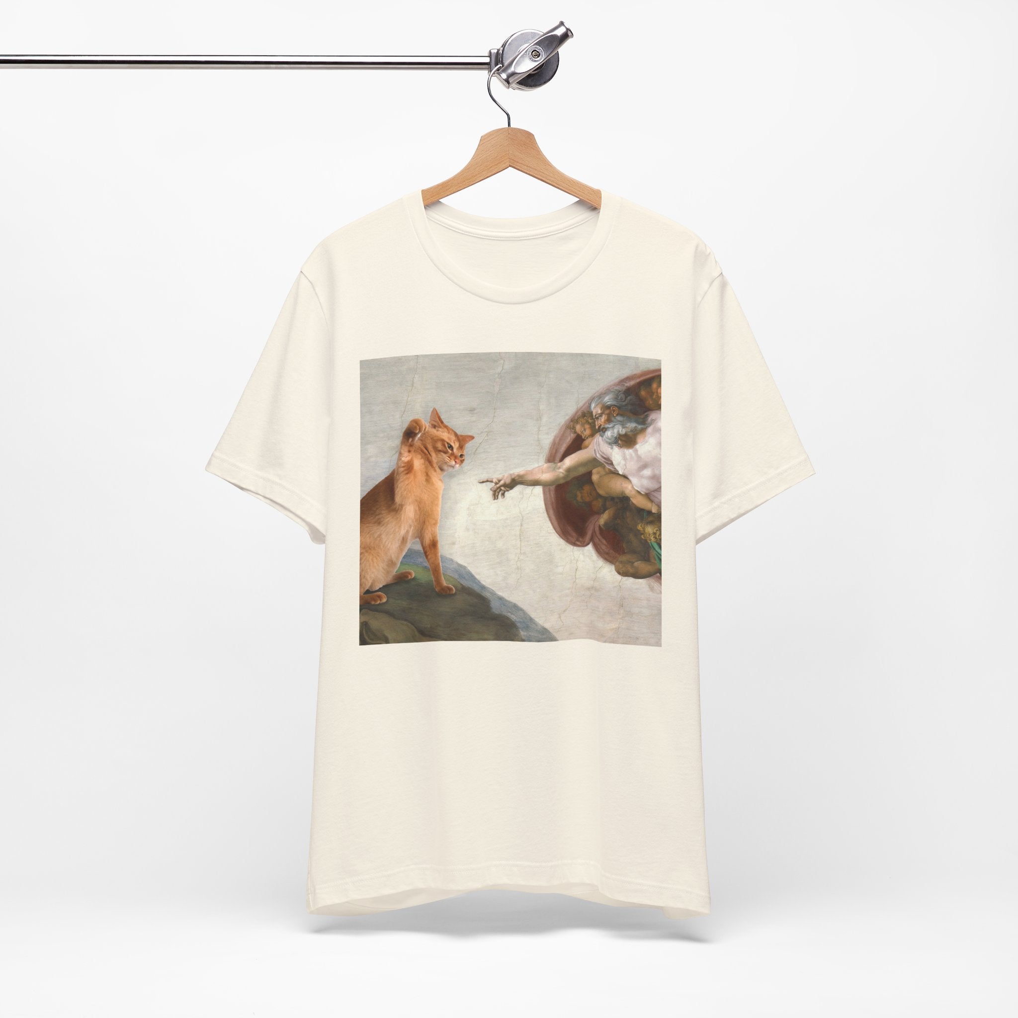 White t-shirt with a graphic of a cat and angel on a hanger against a white background