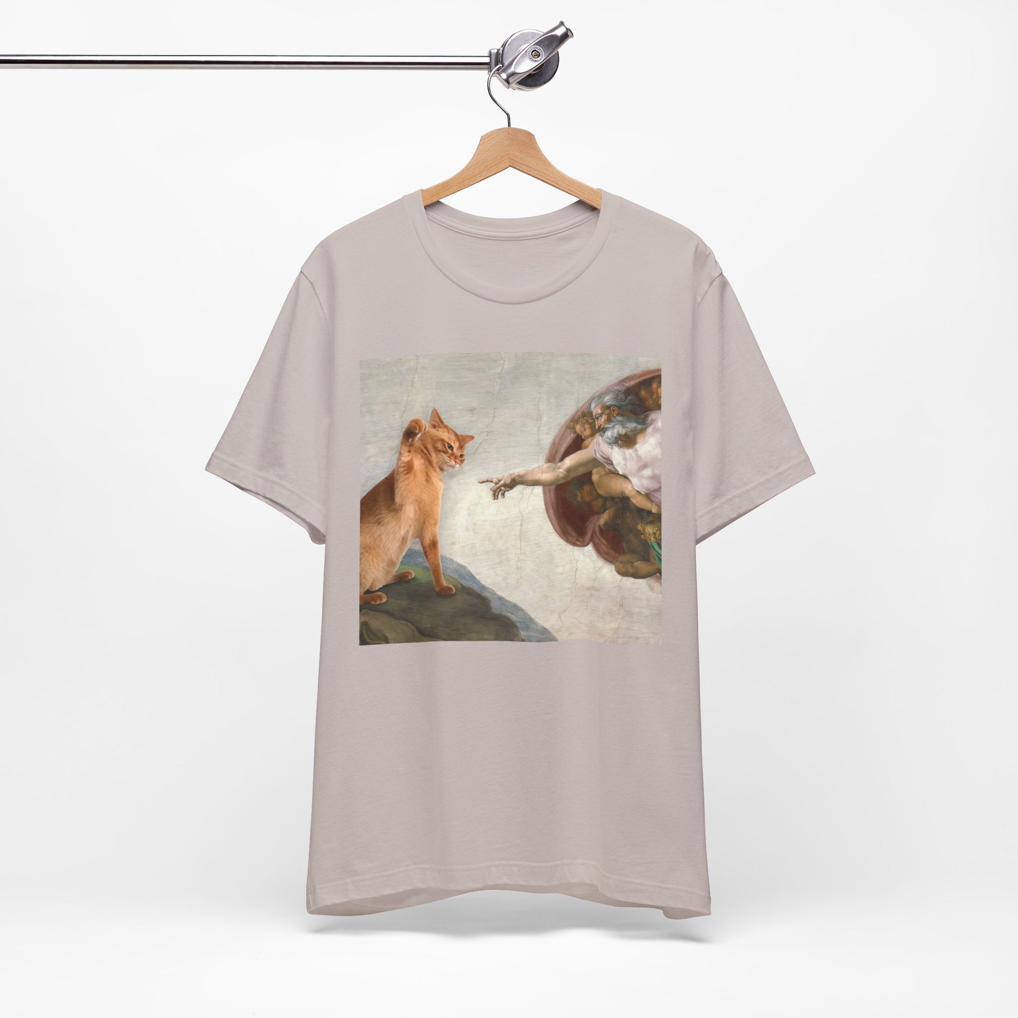 T-shirt with a graphic design of a cat and angel on a hanger against a white background