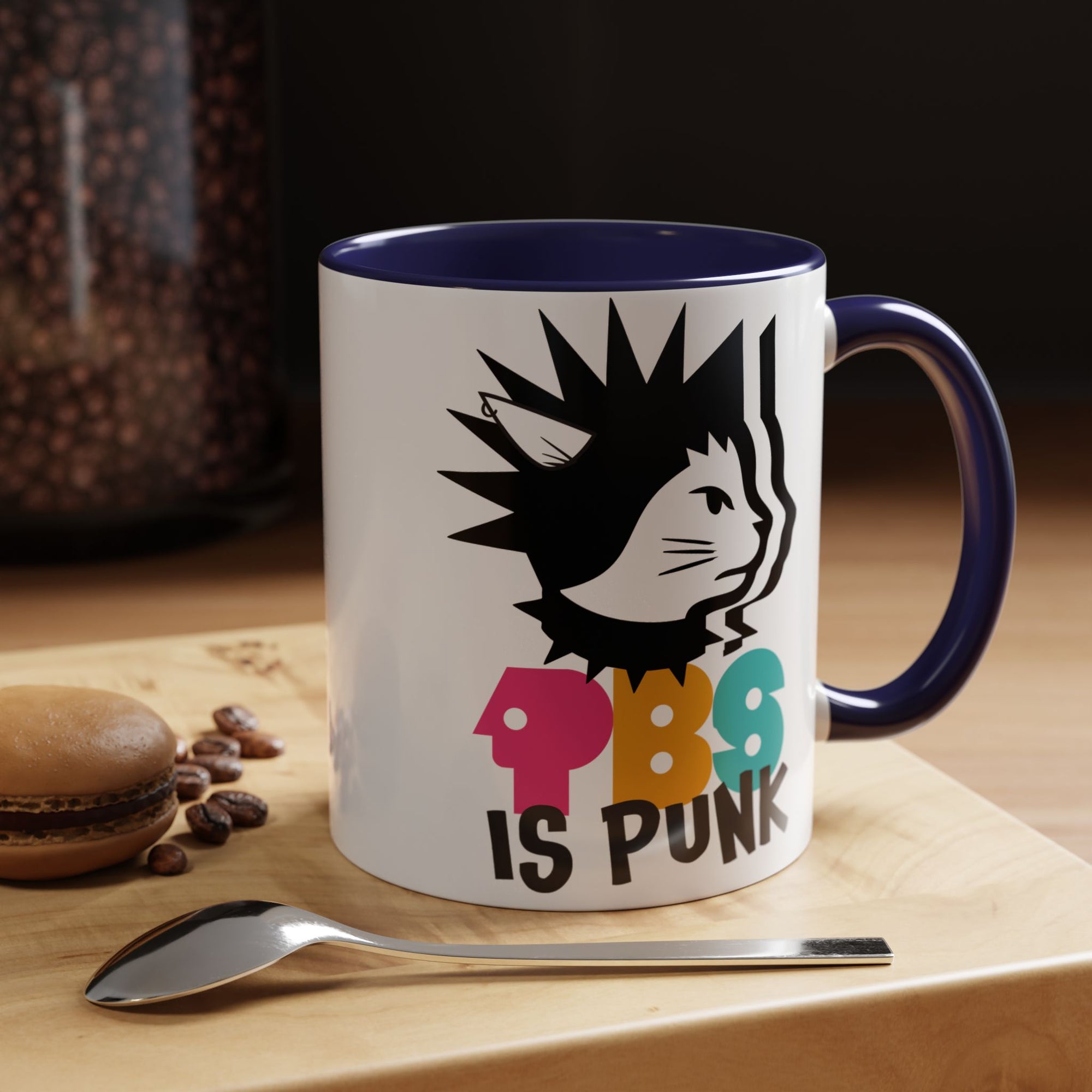 Mug with a colorful design and text on a wooden surface with coffee beans and a spoon.