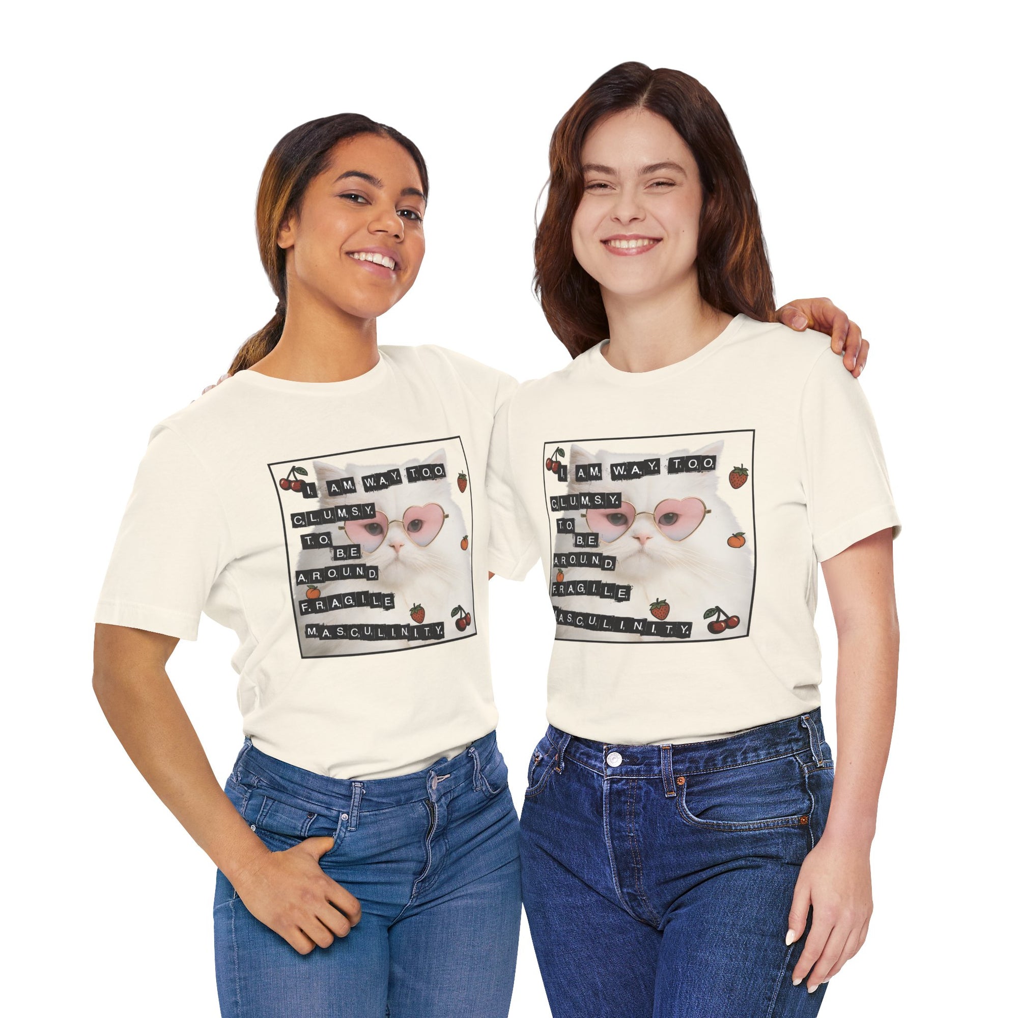 Two women wearing matching white t-shirt featuring a fluffy white cat in pink heart-shaped sunglasses with ransom-note style text that says “I am way too clumsy to be around fragile masculinity.”