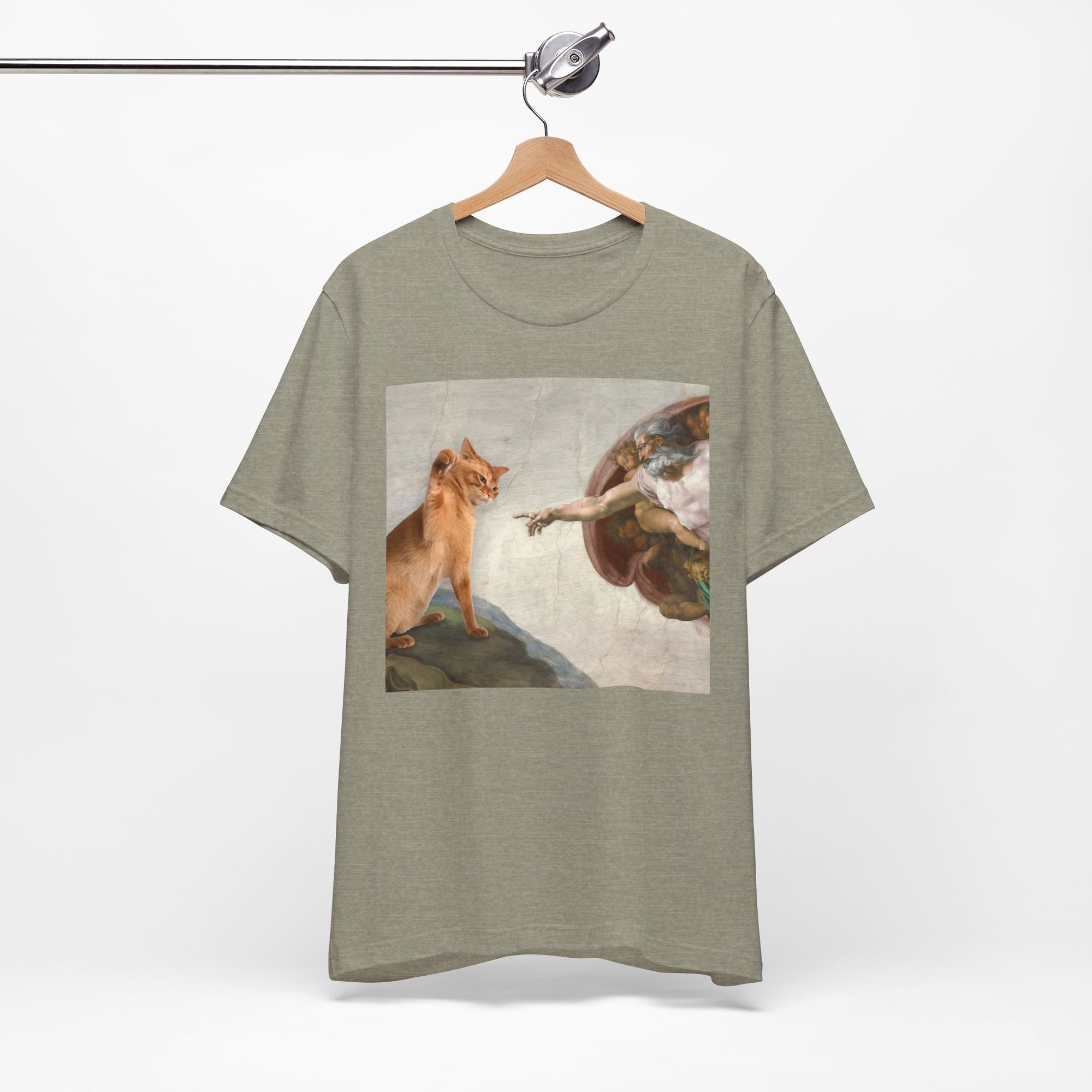 Green t-shirt with a graphic design of a cat and a classical painting on a hanger against a white background
