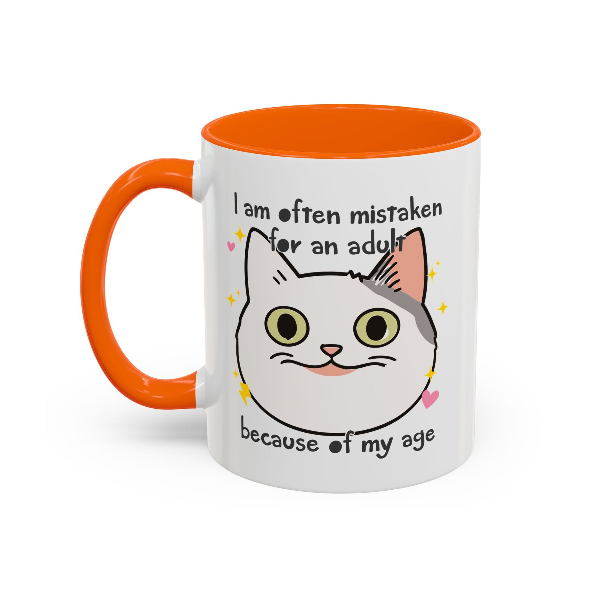 White ceramic mug with orange handle and interior featuring a cute wide-eyed cat face, hearts, sparkles, and the phrase “I am often mistaken for an adult because of my age.”
