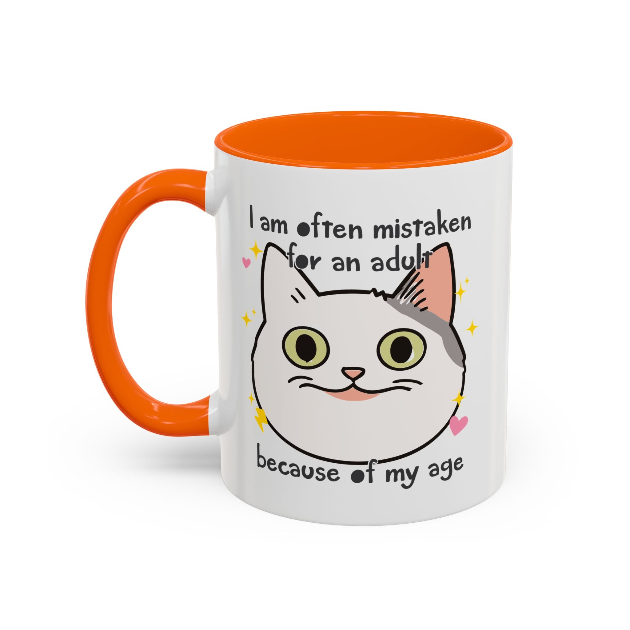 White ceramic mug with orange handle and interior featuring a cute wide-eyed cat face, hearts, sparkles, and the phrase “I am often mistaken for an adult because of my age.”
