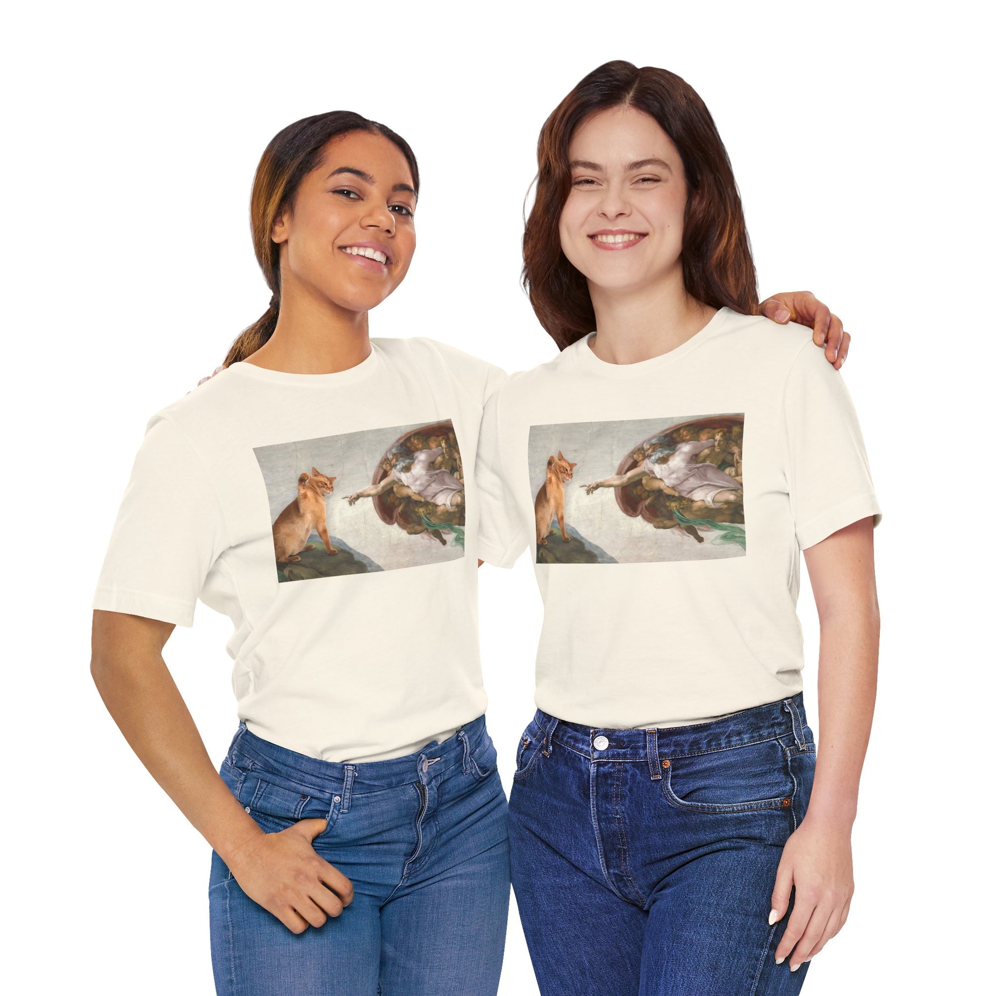 Two women wearing matching white t-shirts with a graphic design of a cat and god on a white background.