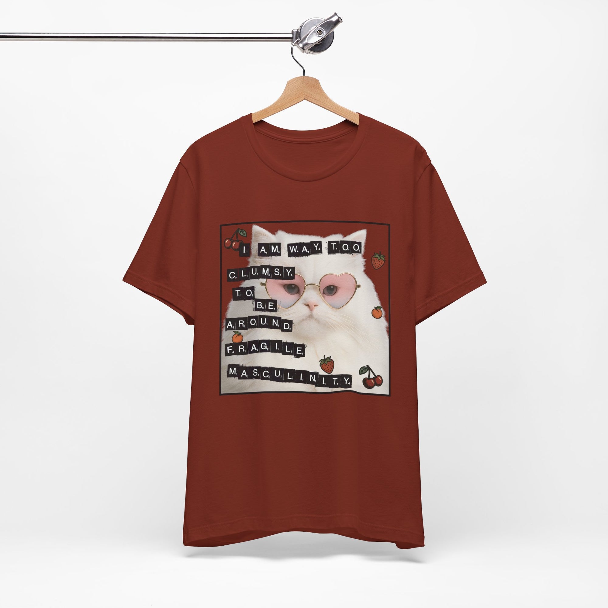Red t-shirt featuring a fluffy white cat in pink heart-shaped sunglasses with ransom-note style text that says “I am way too clumsy to be around fragile masculinity.”