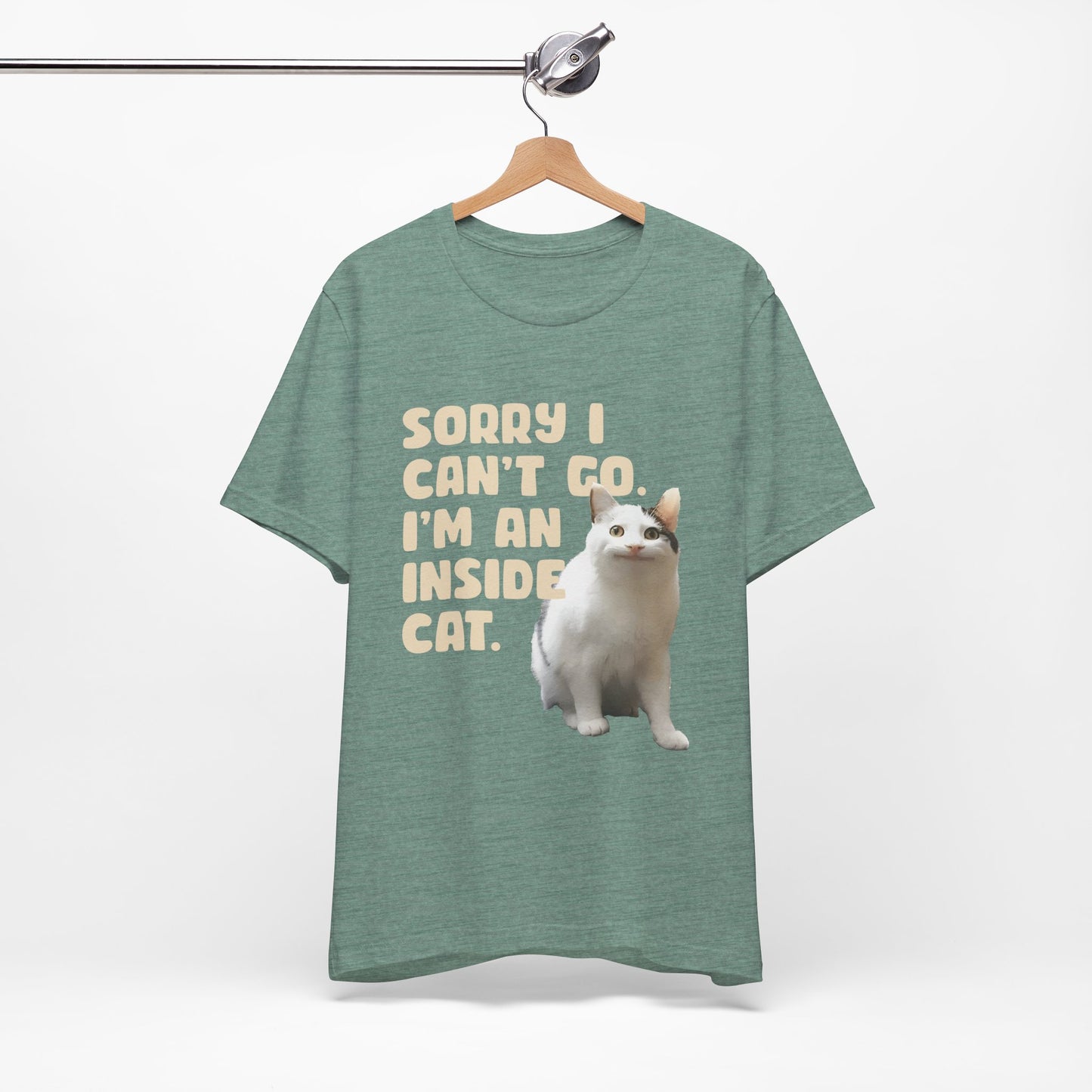 Green t-shirt with a cat graphic and text on a hanger against a white background