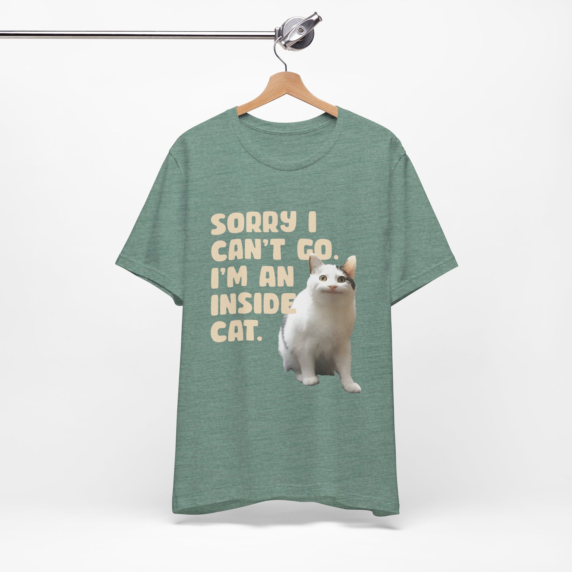 Green t-shirt with a cat graphic and text on a hanger against a white background