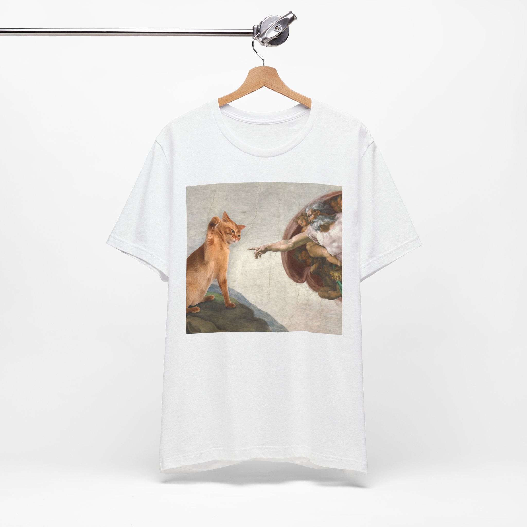 White t-shirt with a graphic design of a cat and angel on a hanger against a white background