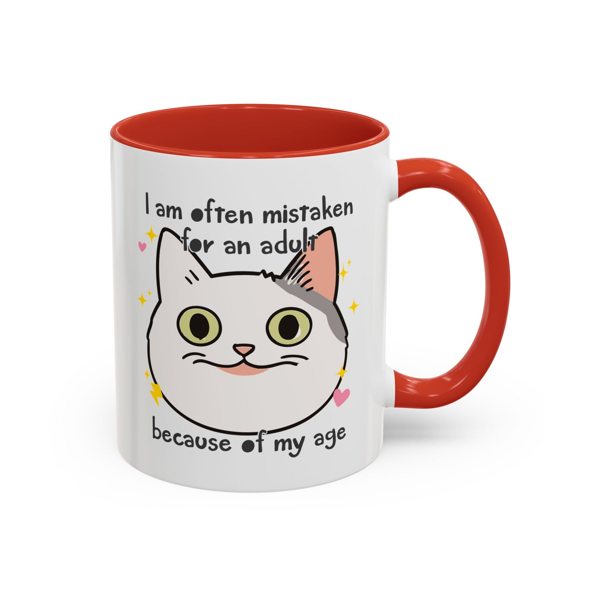 White ceramic mug with red handle and interior featuring a cute wide-eyed cat face, hearts, sparkles, and the phrase “I am often mistaken for an adult because of my age.”
