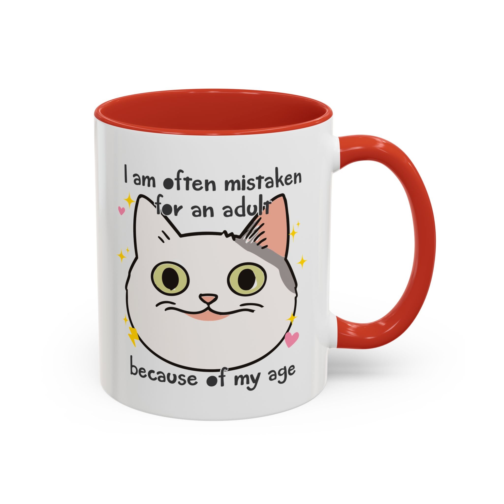 White ceramic mug with red handle and interior featuring a cute wide-eyed cat face, hearts, sparkles, and the phrase “I am often mistaken for an adult because of my age.”

