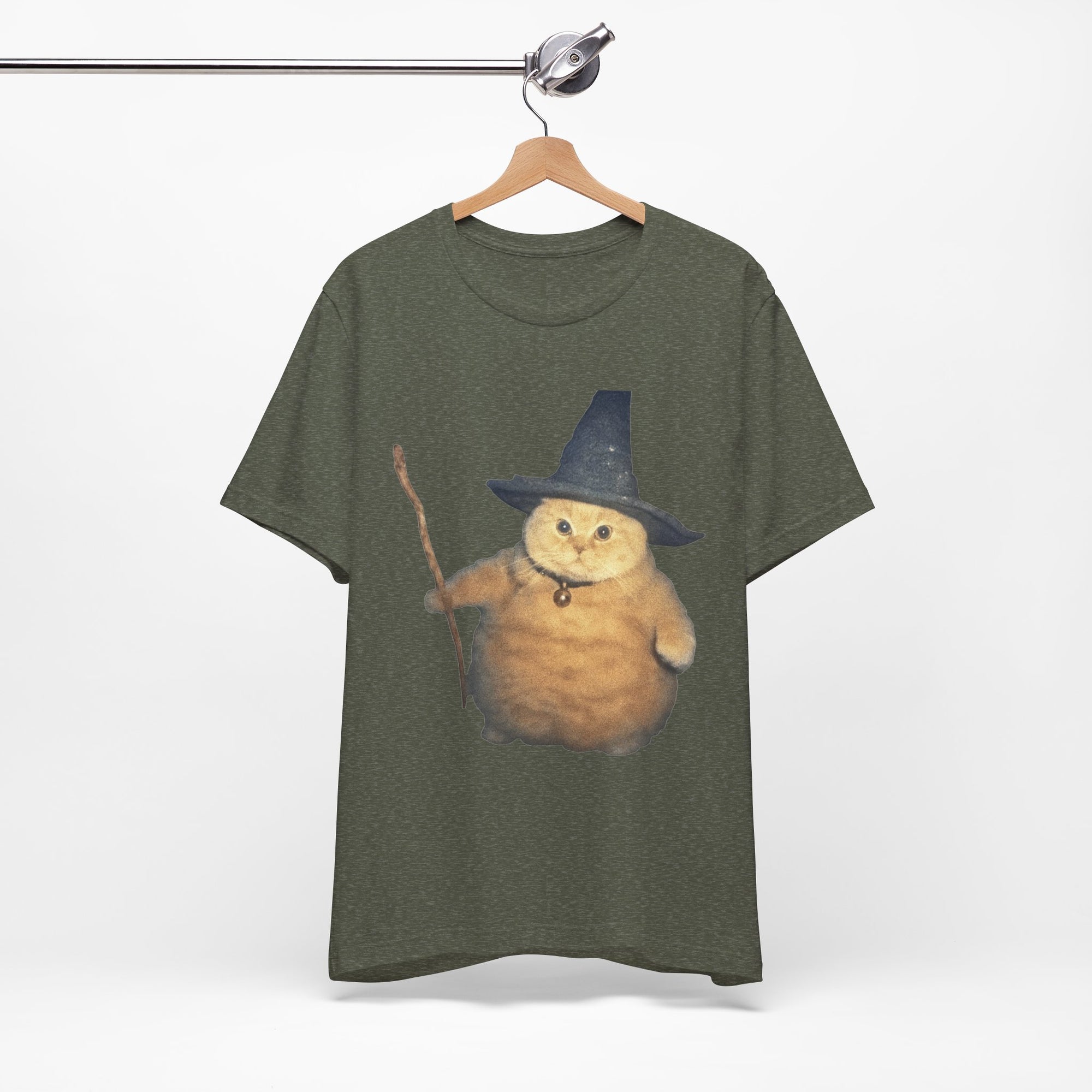 Green t-shirt with a cat wearing a wizard hat and holding a wand on a hanger against a white background.