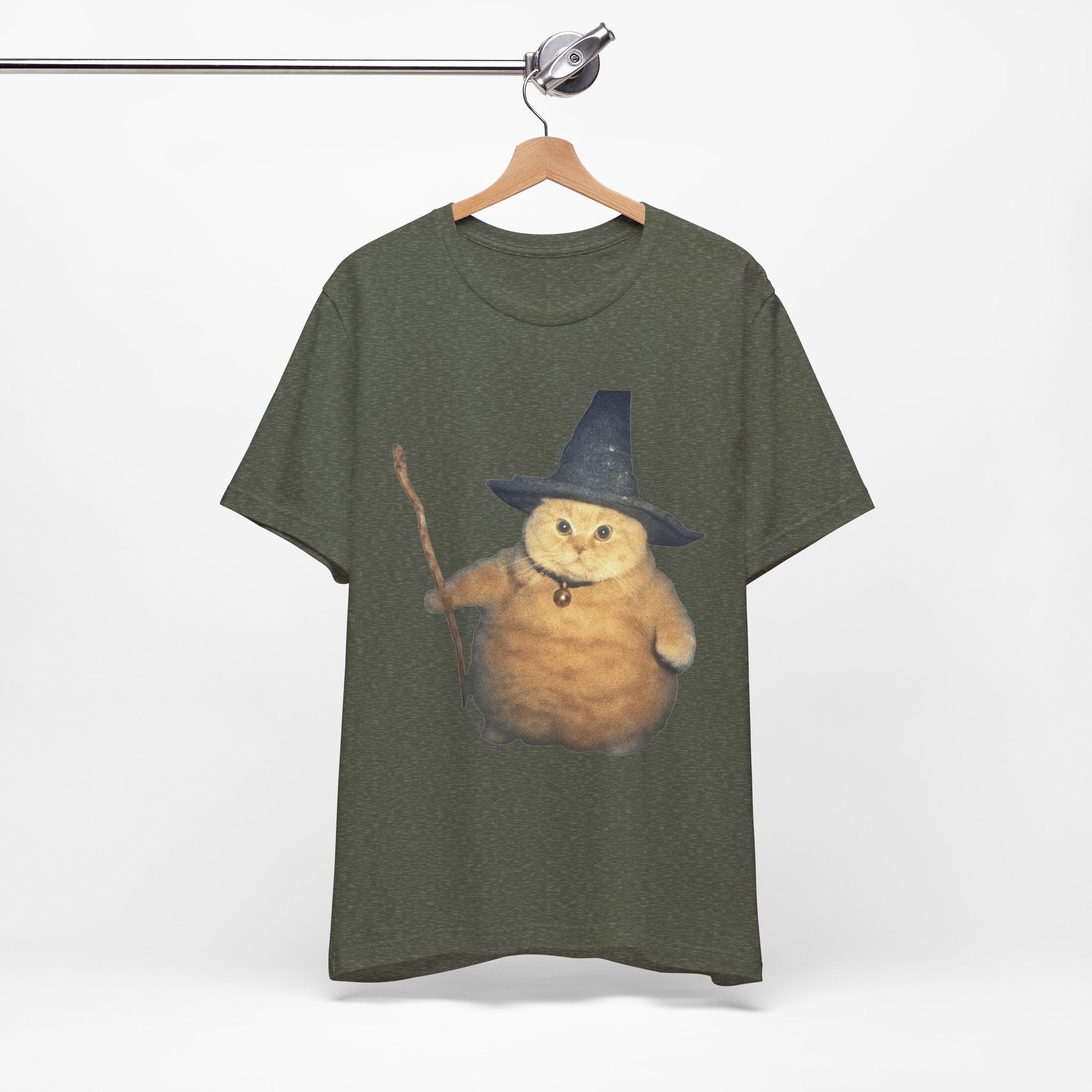 Green t-shirt with a cat wearing a wizard hat and holding a wand on a hanger against a white background.