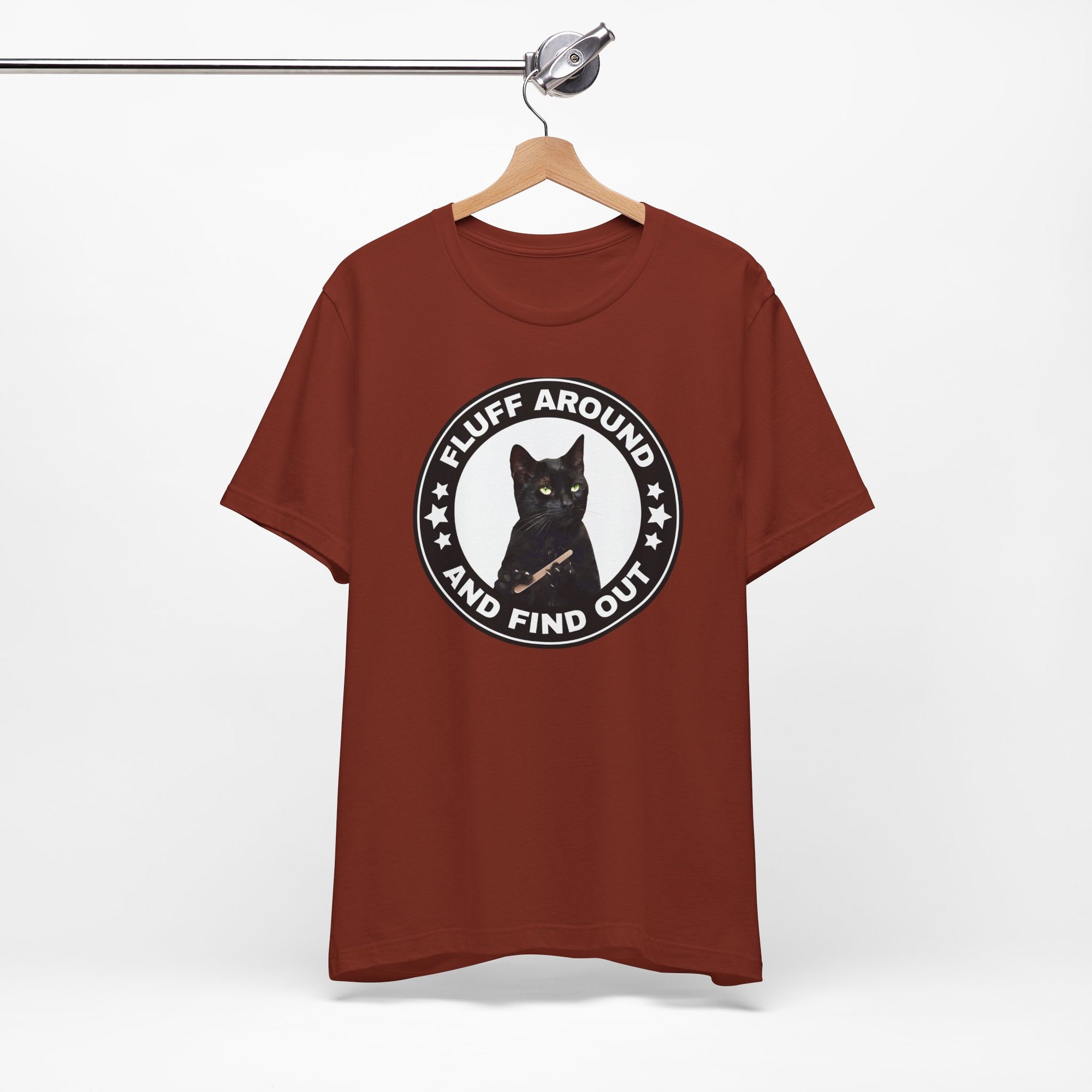 red t-shirt featuring a circular badge design with a black cat and the phrase “Fluff Around and Find Out.”
