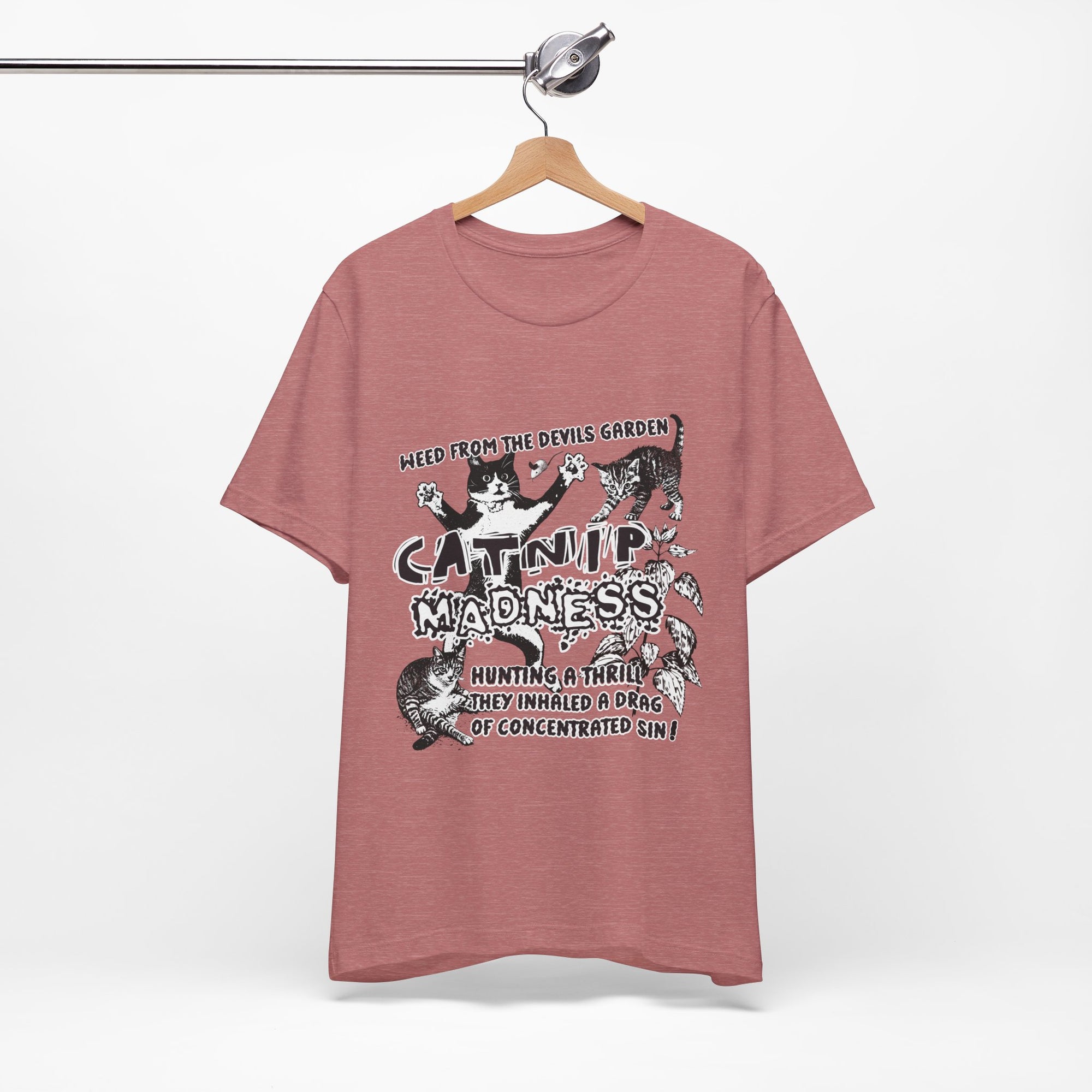 Pink t-shirt with graphic design and text on a hanger against a white background
