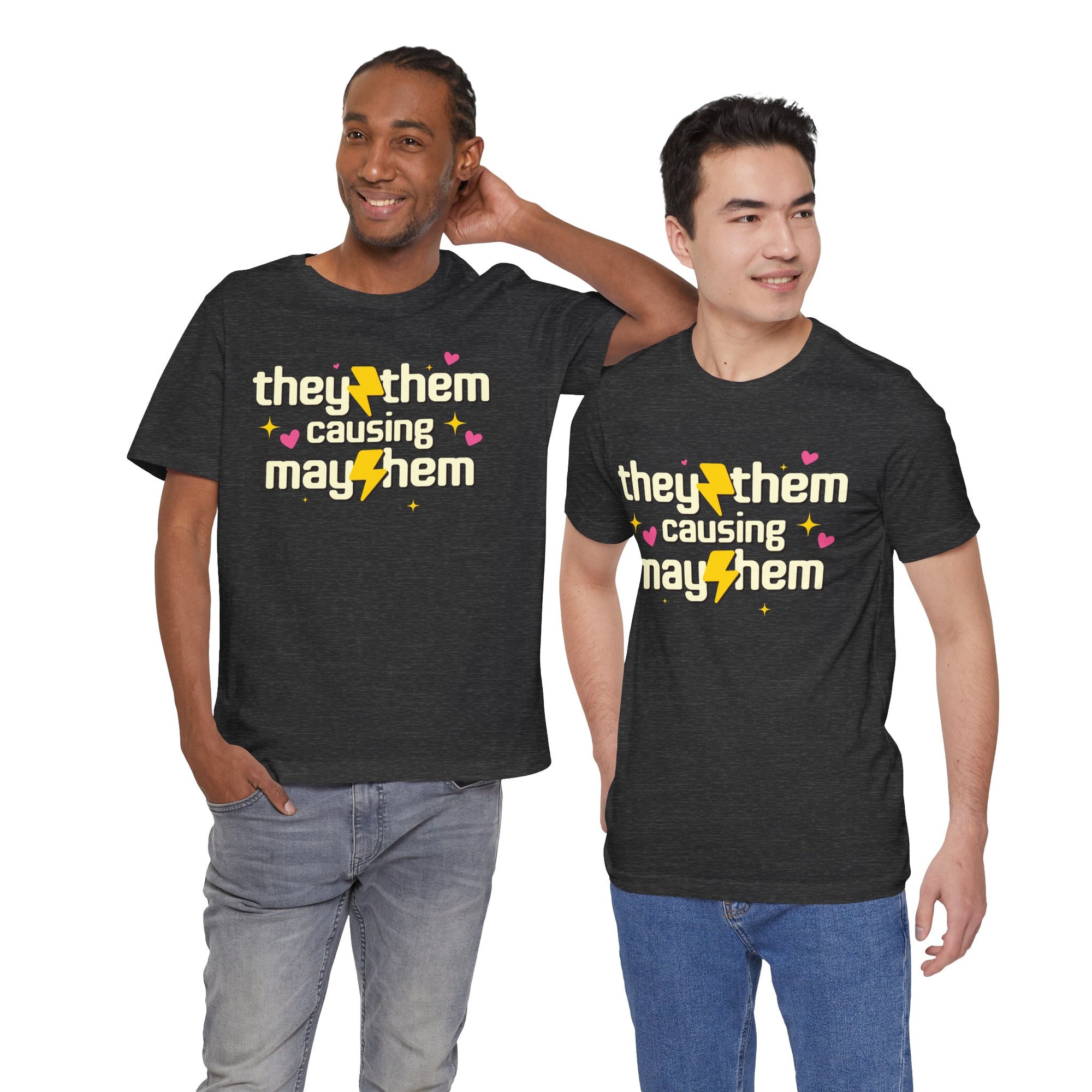 black t-shirt featuring the phrase “They/Them Causing Mayhem” in retro-style lettering with yellow lightning bolts, pink hearts, and sparkle accents.
