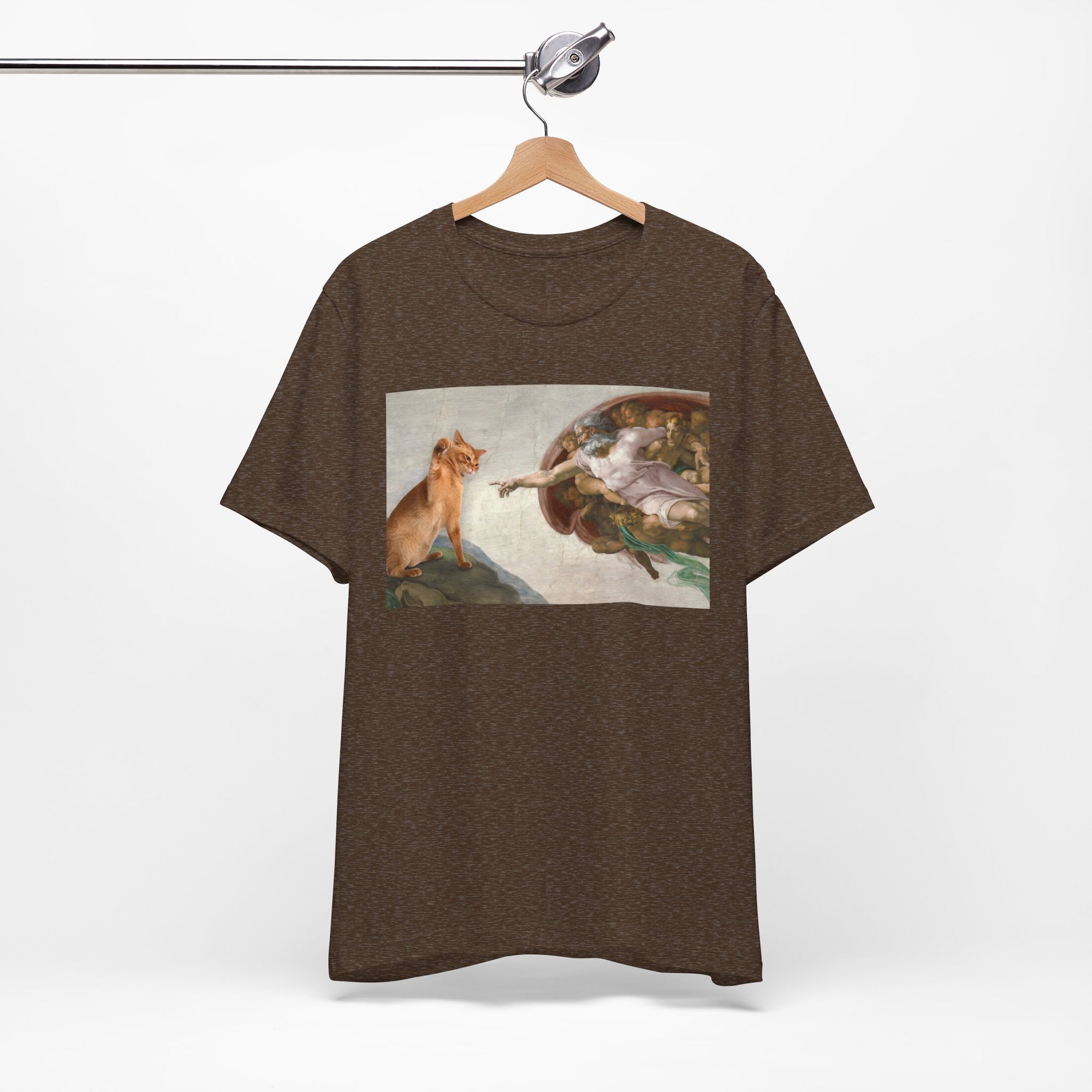Brown t-shirt with a graphic of a cat and god on a hanger against a white background