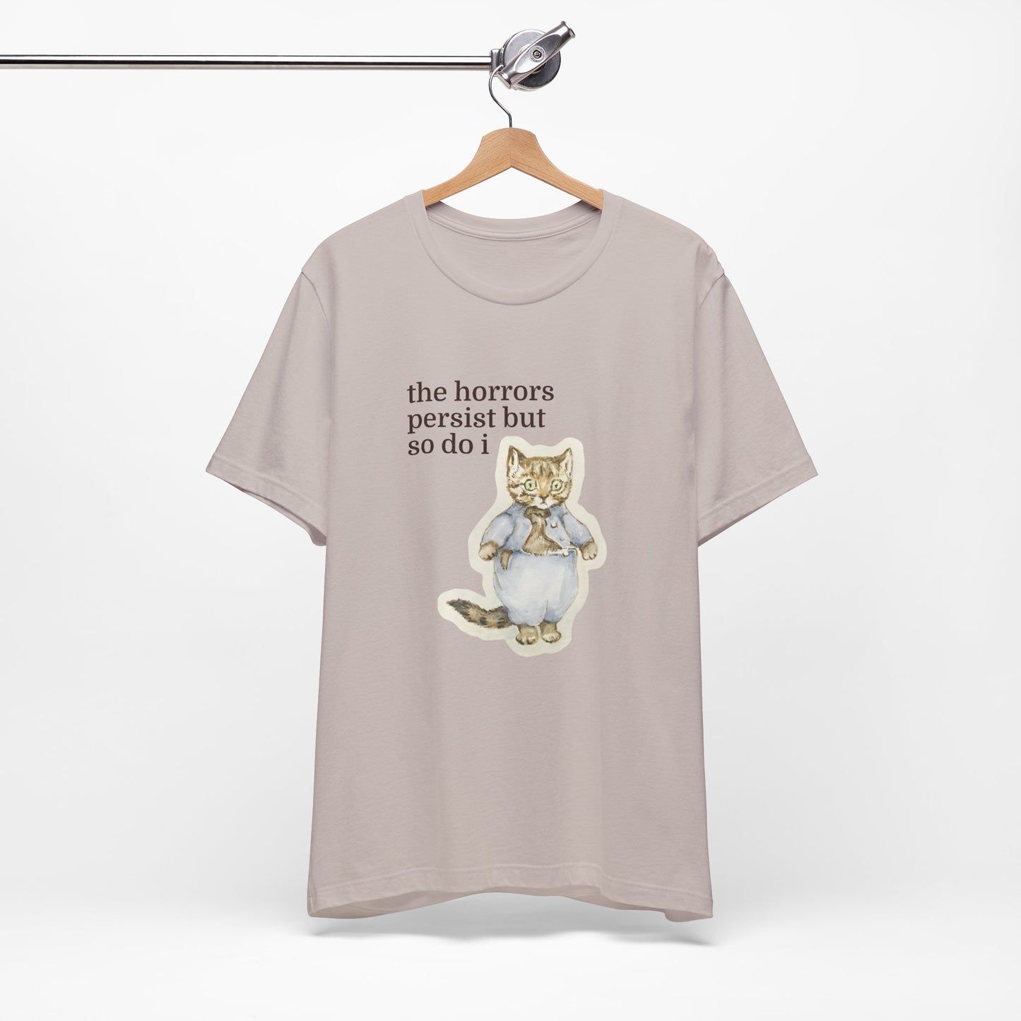 Beige t-shirt featuring a vintage-style illustrated cat in blue clothing with the phrase “the horrors persist but so do i.”