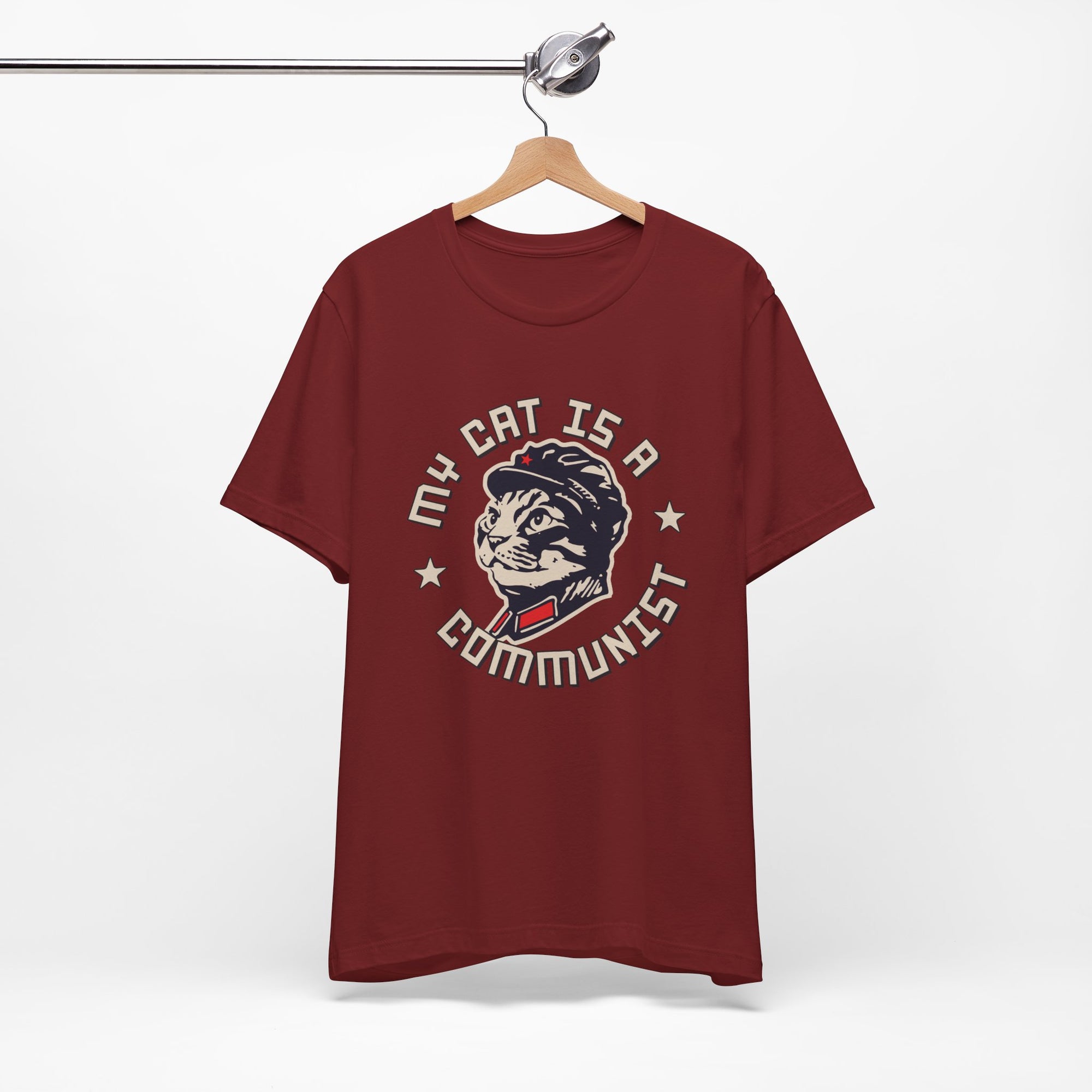 Maroon t-shirt with a graphic design of a cat and text on a hanger against a white background