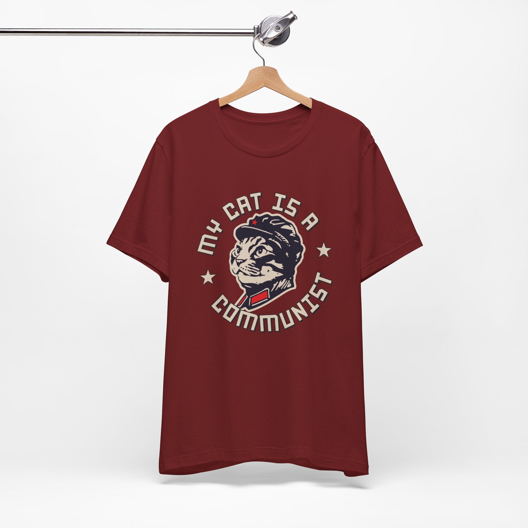 Maroon t-shirt with a graphic design of a cat and text on a hanger against a white background