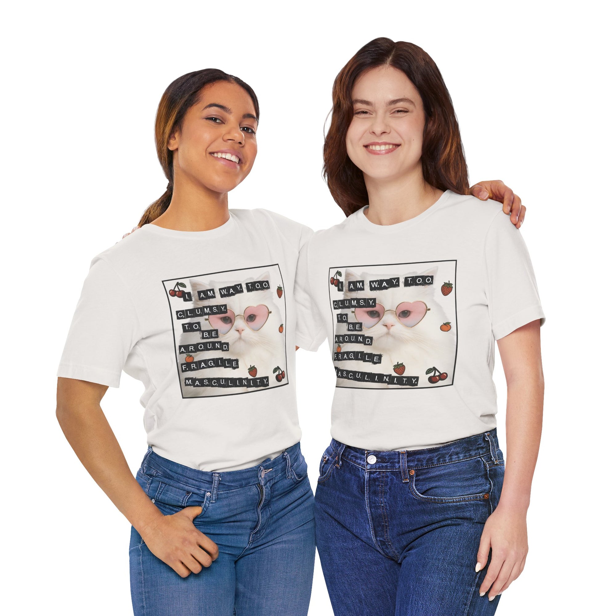 Two women wearing white t-shirt featuring a fluffy white cat in pink heart-shaped sunglasses with ransom-note style text that says “I am way too clumsy to be around fragile masculinity.”