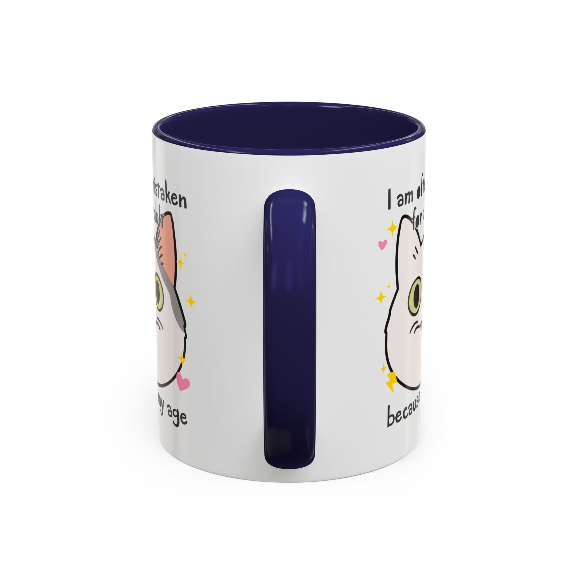 White ceramic mug with purple handle and interior featuring a cute wide-eyed cat face, hearts, sparkles, and the phrase “I am often mistaken for an adult because of my age.”
