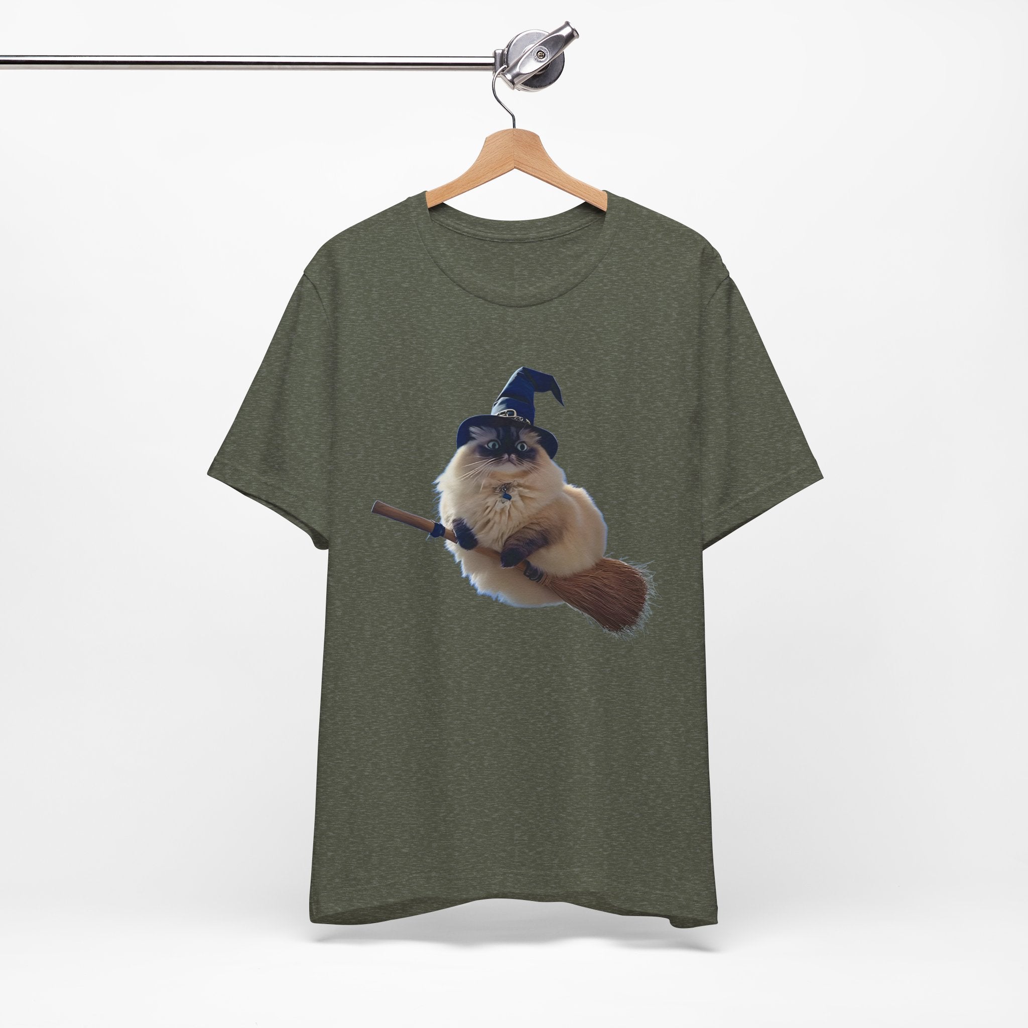 Green t-shirt with a graphic of a cat in a witch hat and broomstick on a hanger against a white background
