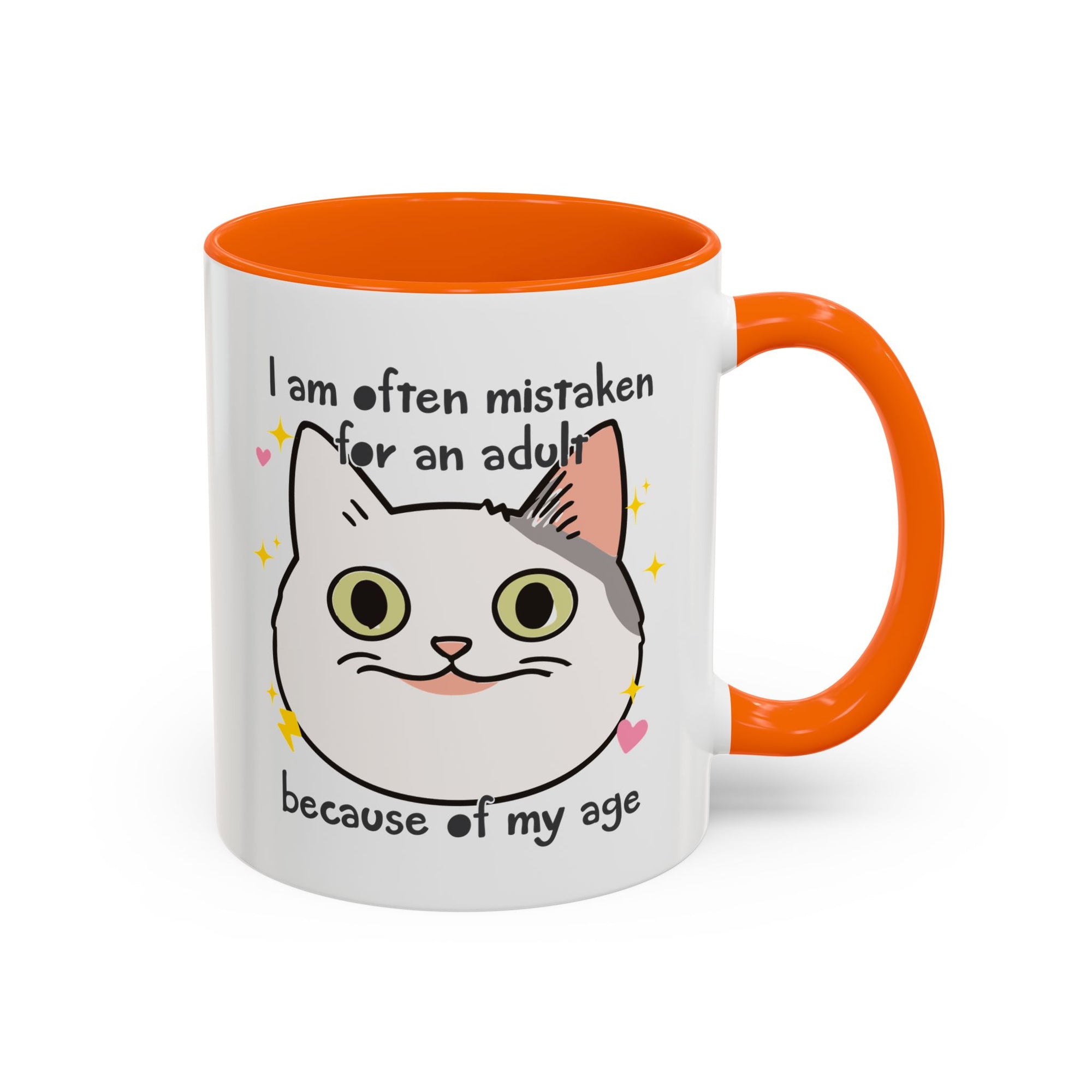 White ceramic mug with orange handle and interior featuring a cute wide-eyed cat face, hearts, sparkles, and the phrase “I am often mistaken for an adult because of my age.”
