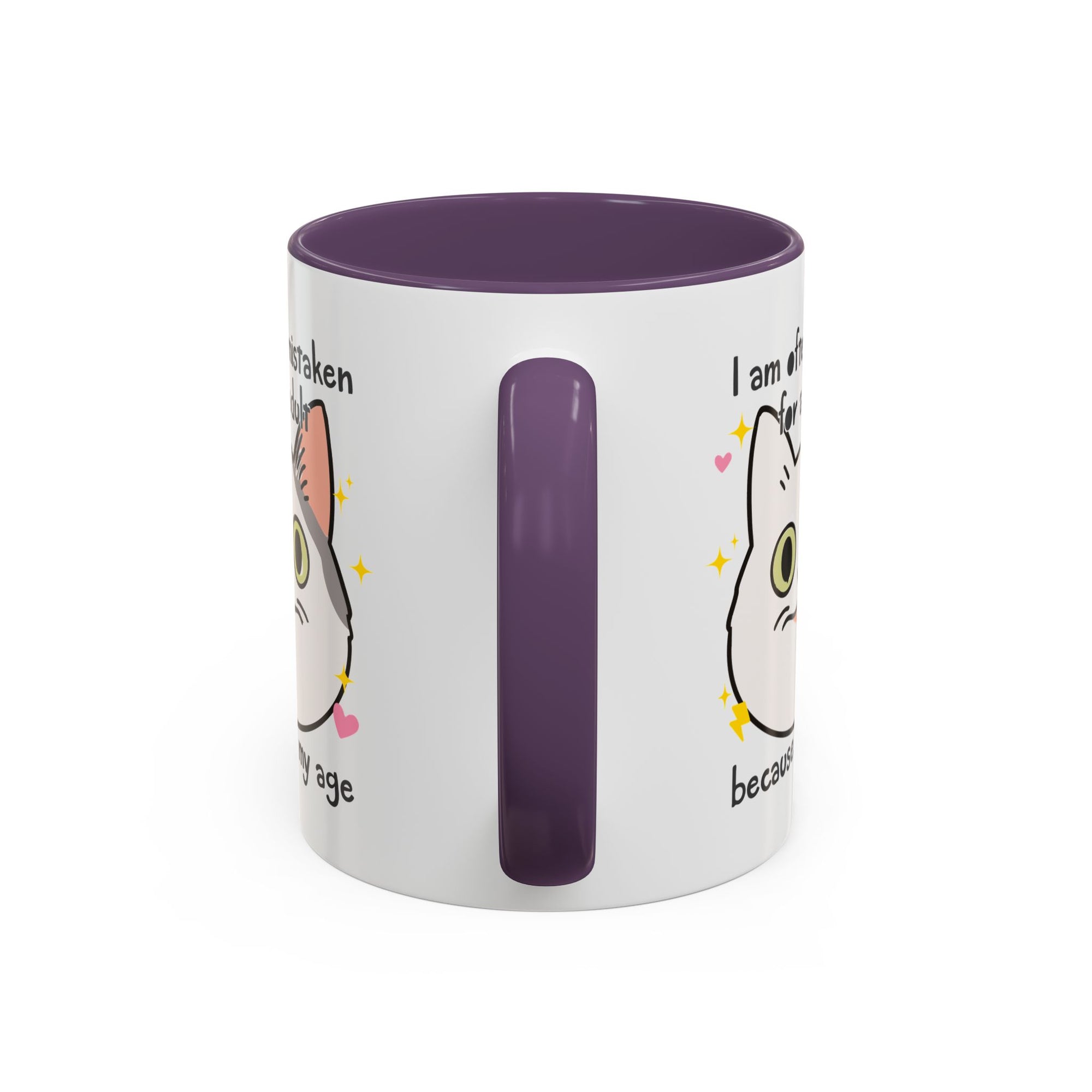 White ceramic mug with purple handle and interior featuring a cute wide-eyed cat face, hearts, sparkles, and the phrase “I am often mistaken for an adult because of my age.”
