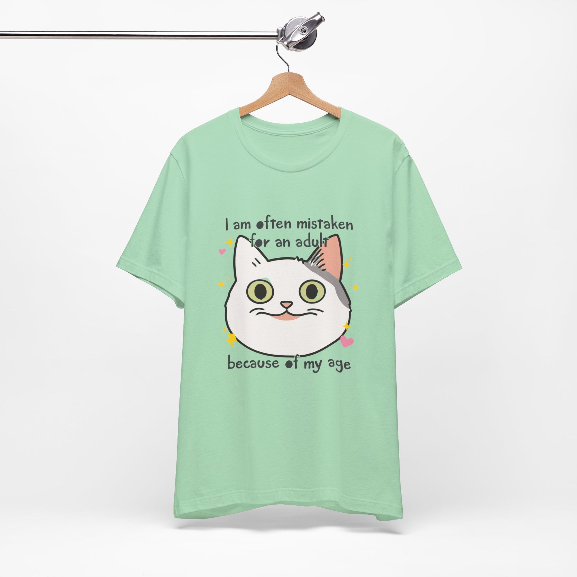 Green t-shirt with a cat graphic and text on a hanger against a white background