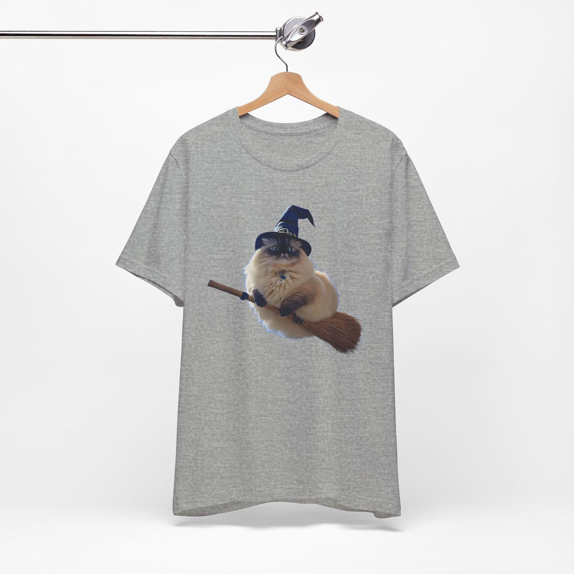 Gray t-shirt with a graphic of a cat in a witch hat and broom on a hanger against a white background