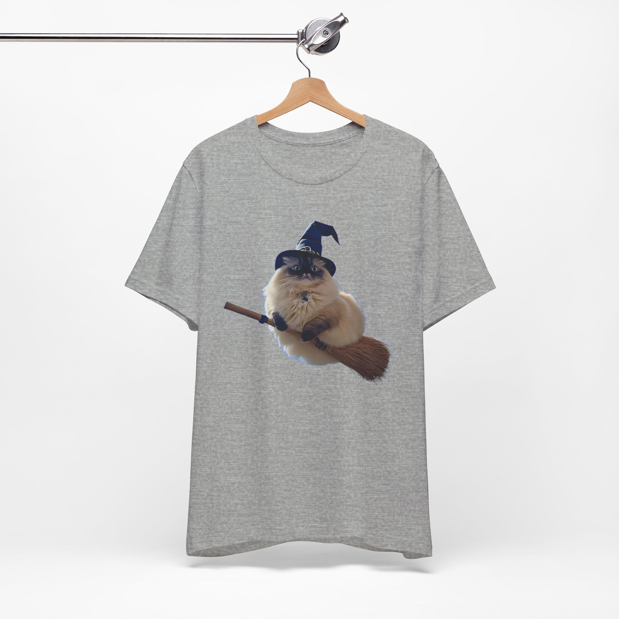 Gray t-shirt with a graphic of a cat in a witch hat and broom on a hanger against a white background