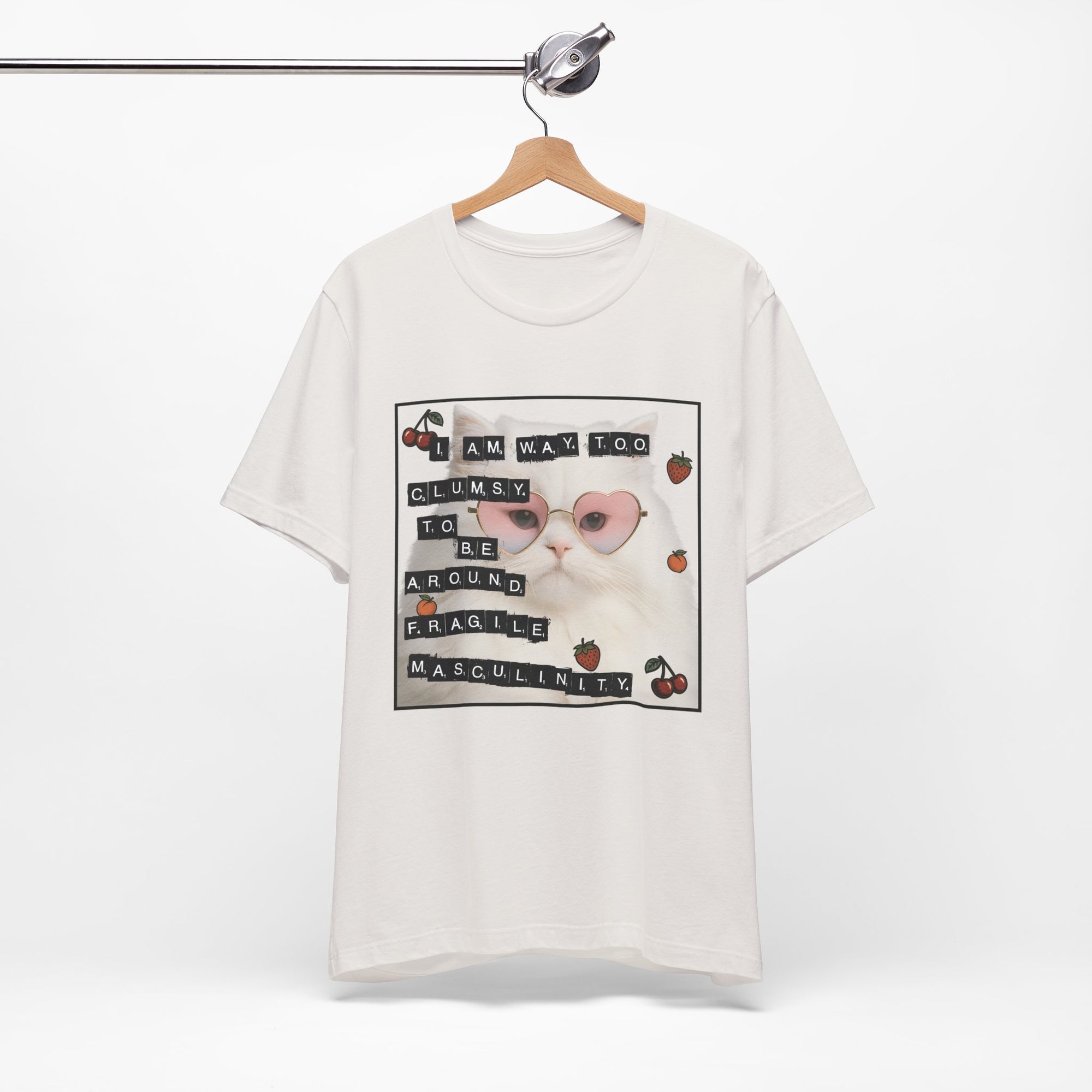 White t-shirt featuring a fluffy white cat in pink heart-shaped sunglasses with ransom-note style text that says “I am way too clumsy to be around fragile masculinity.”