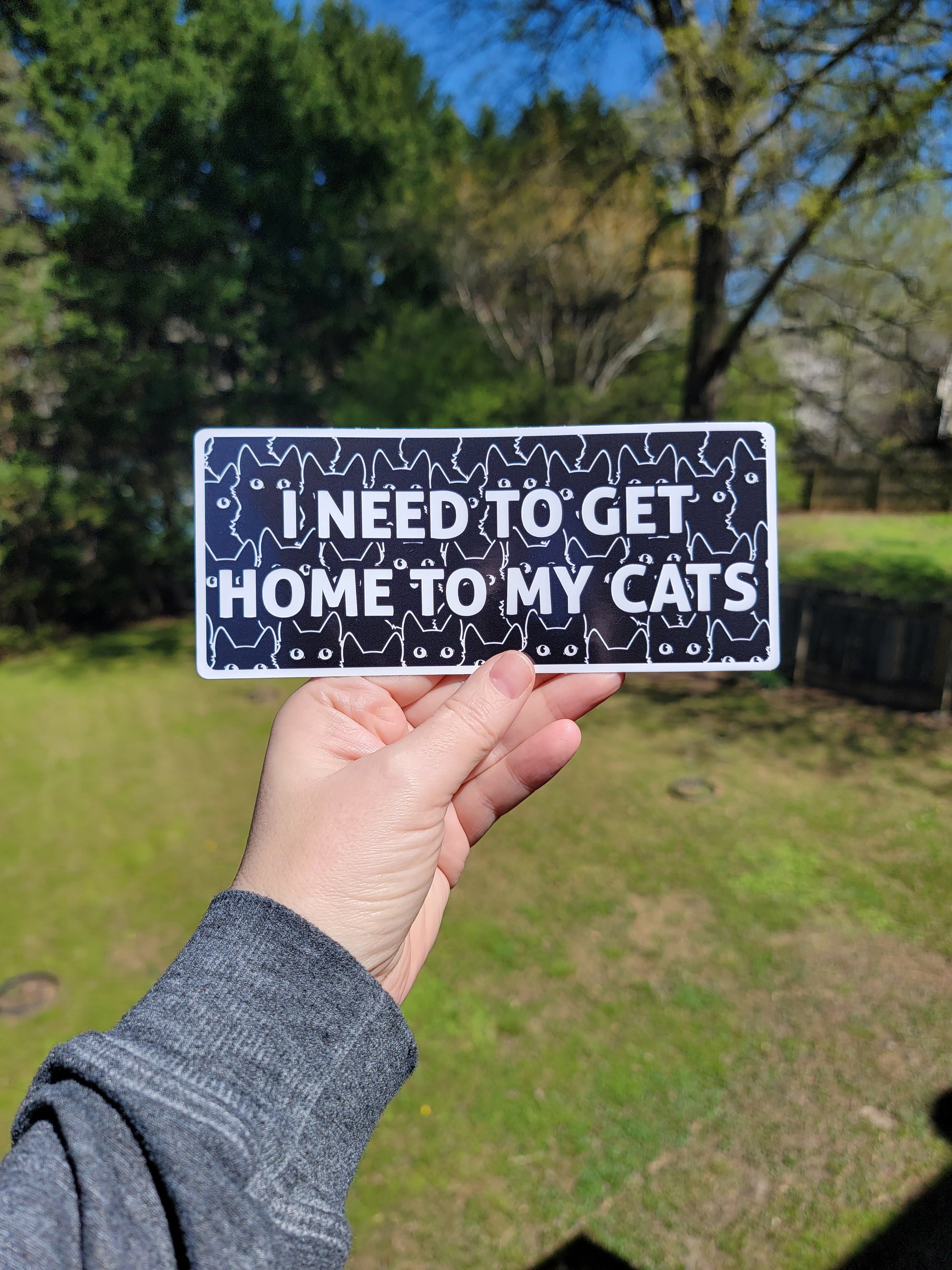 I Need to Get Home to My Cats bumper sticker with bold text, black cat pattern. Waterproof weatherproof vinyl sticker.
