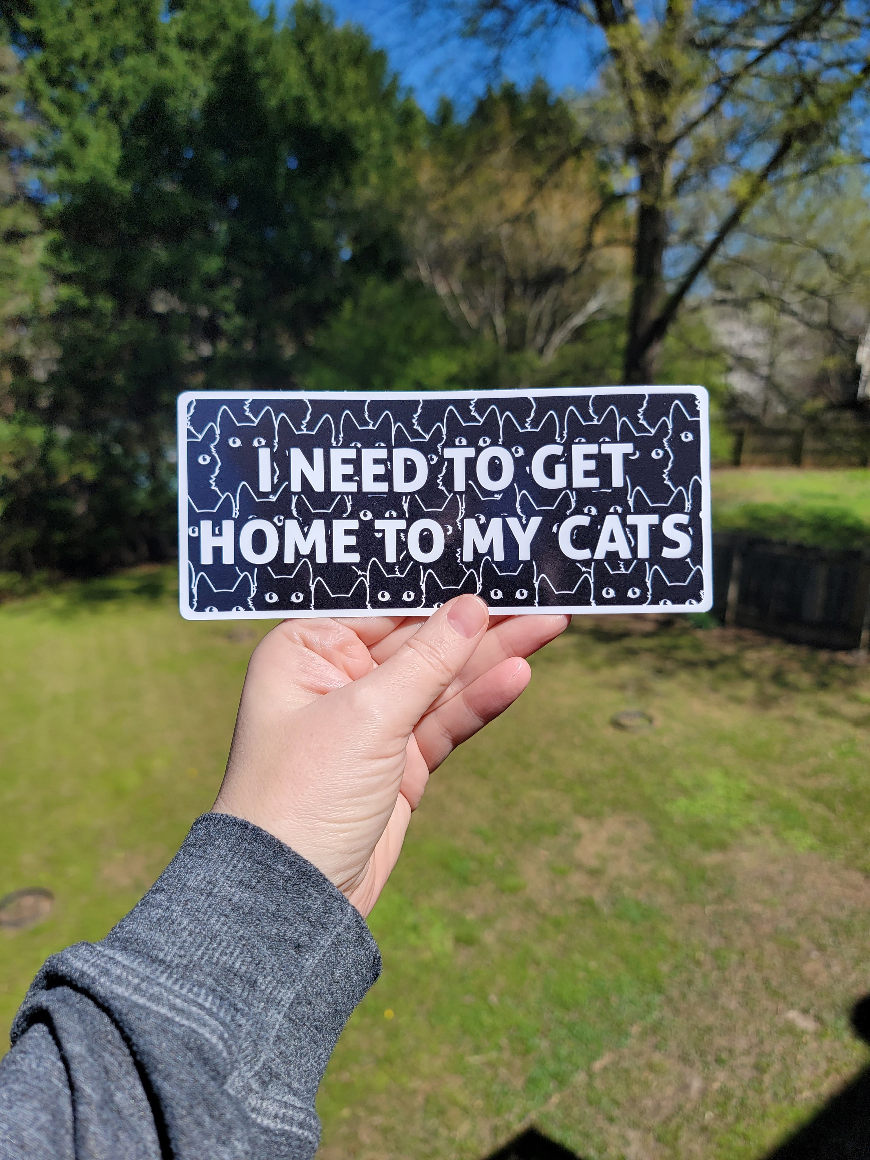 I Need to Get Home to My Cats bumper sticker with bold text, black cat pattern. Waterproof weatherproof vinyl sticker.

