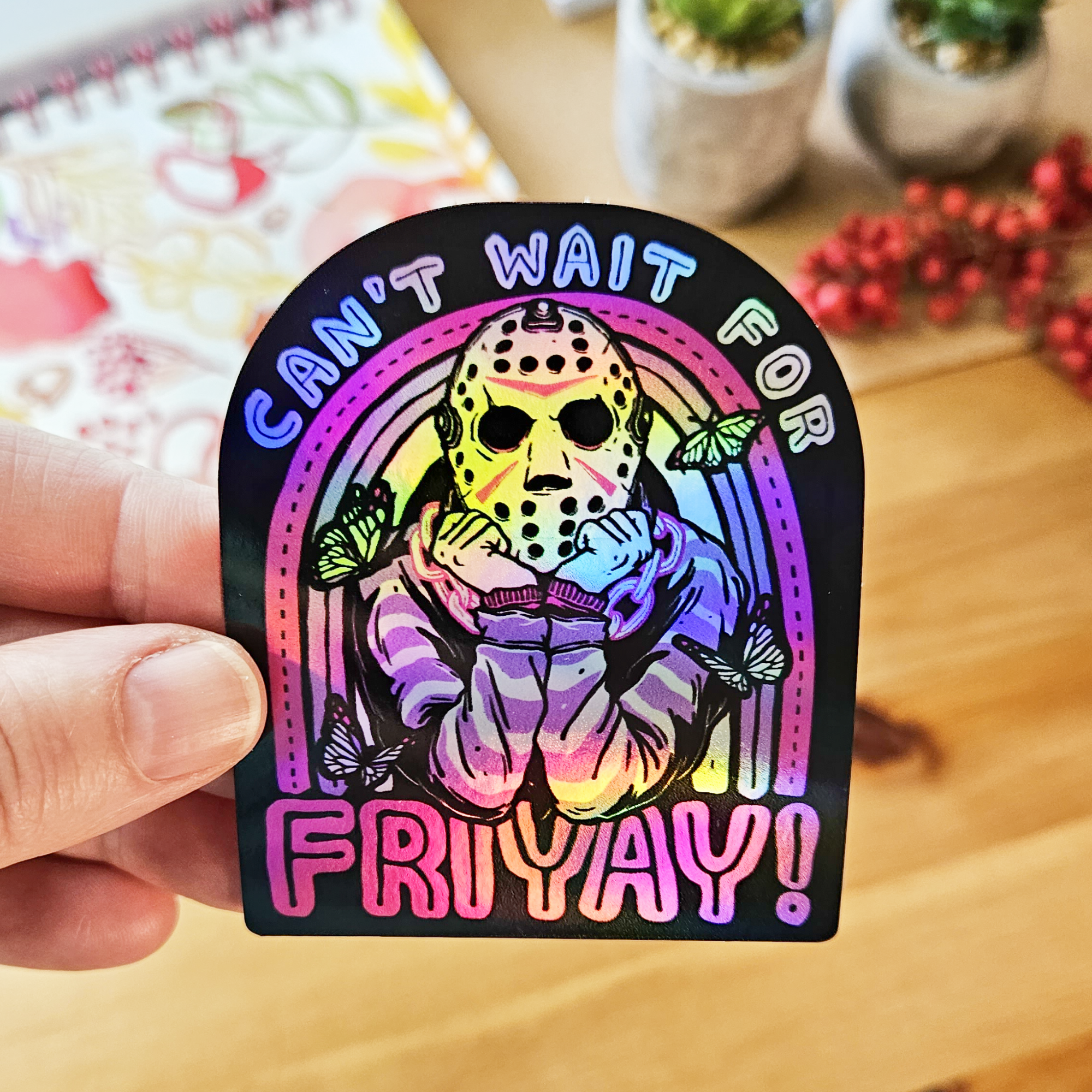 Die cut sticker featuring a horror-inspired masked character with butterflies, colorful retro artwork, and the phrase “Can’t Wait for Friyay!”

